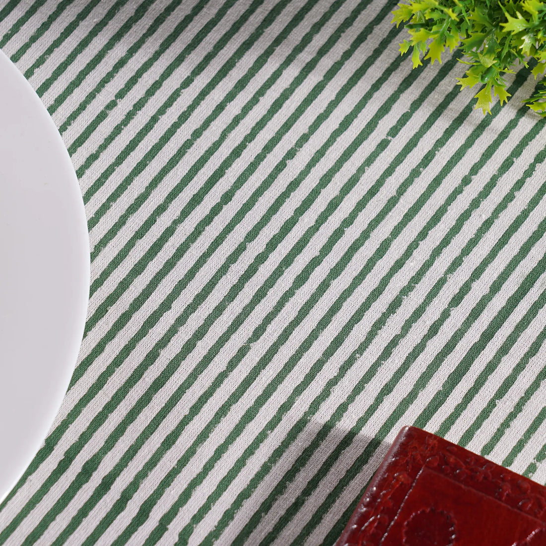 Green and white striped placemat with a plant and plate on a table