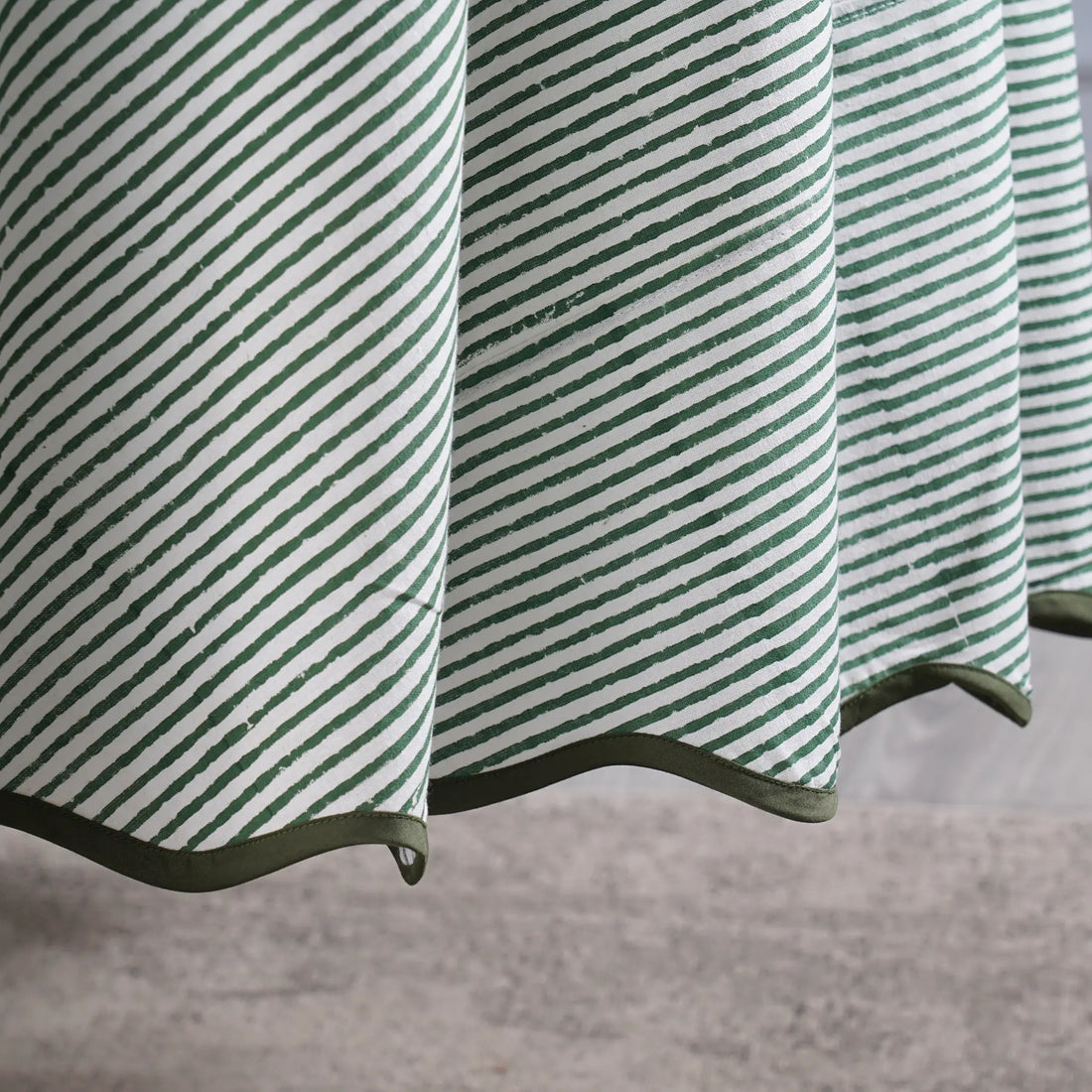 Green and white striped fabric with a textured pattern on a neutral background
