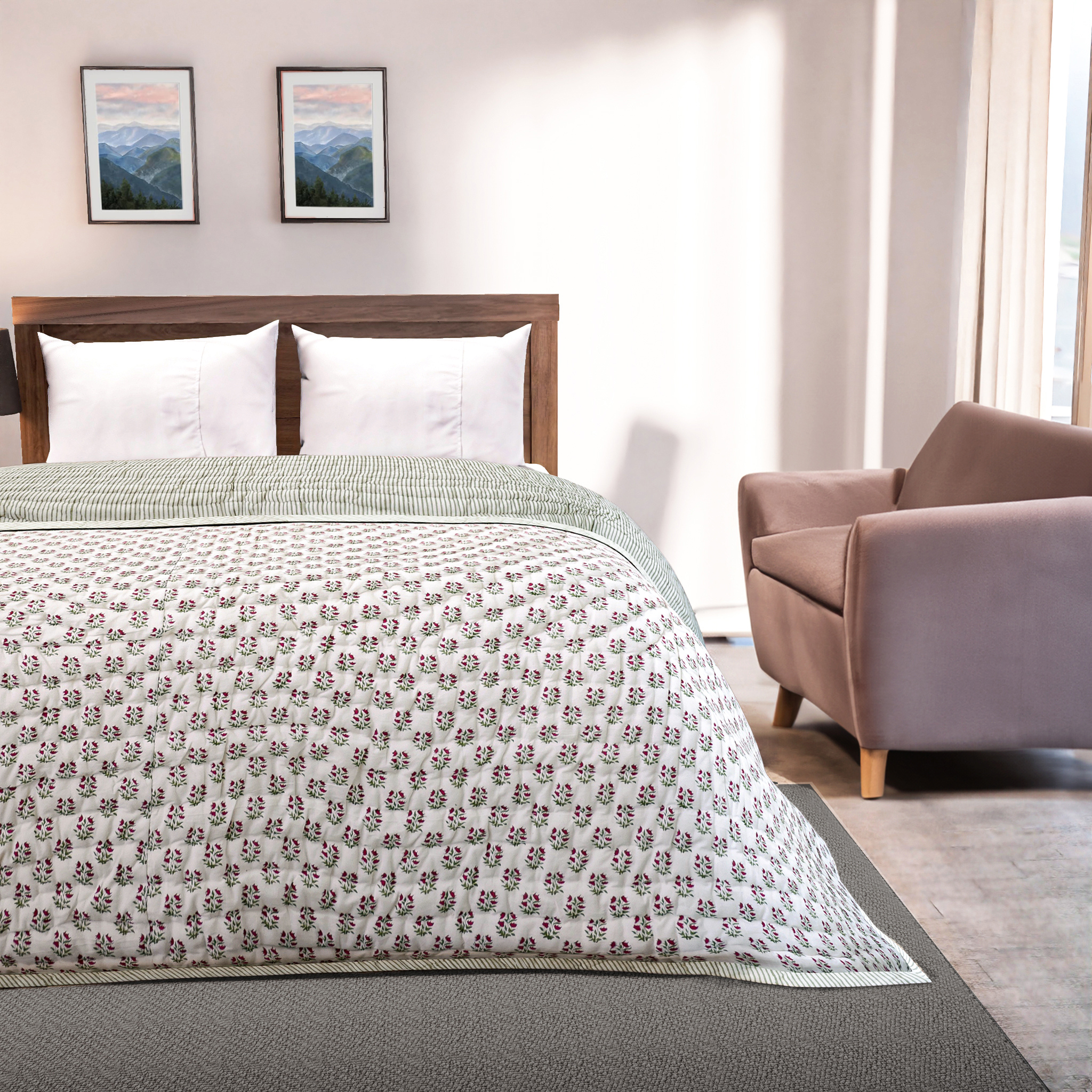 Bedroom with a bed featuring a floral-patterned comforter, a chair, and framed pictures on the wall.