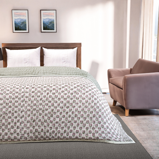 Bedroom with a bed featuring a floral-patterned comforter, a chair, and framed pictures on the wall.