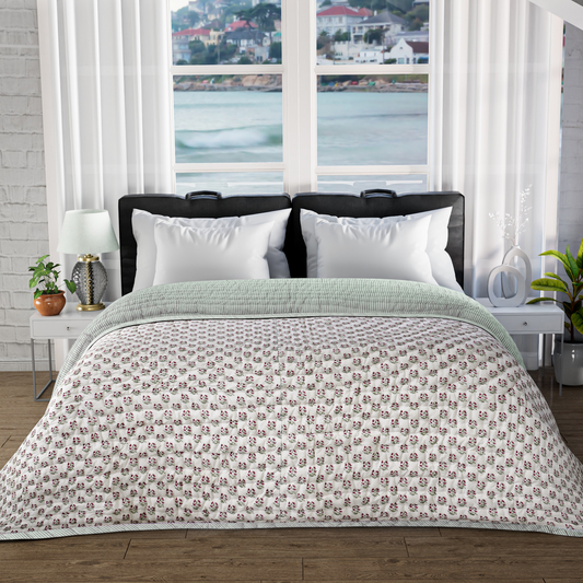 Bed with floral-patterned comforter in a room with large windows showing a waterfront view.