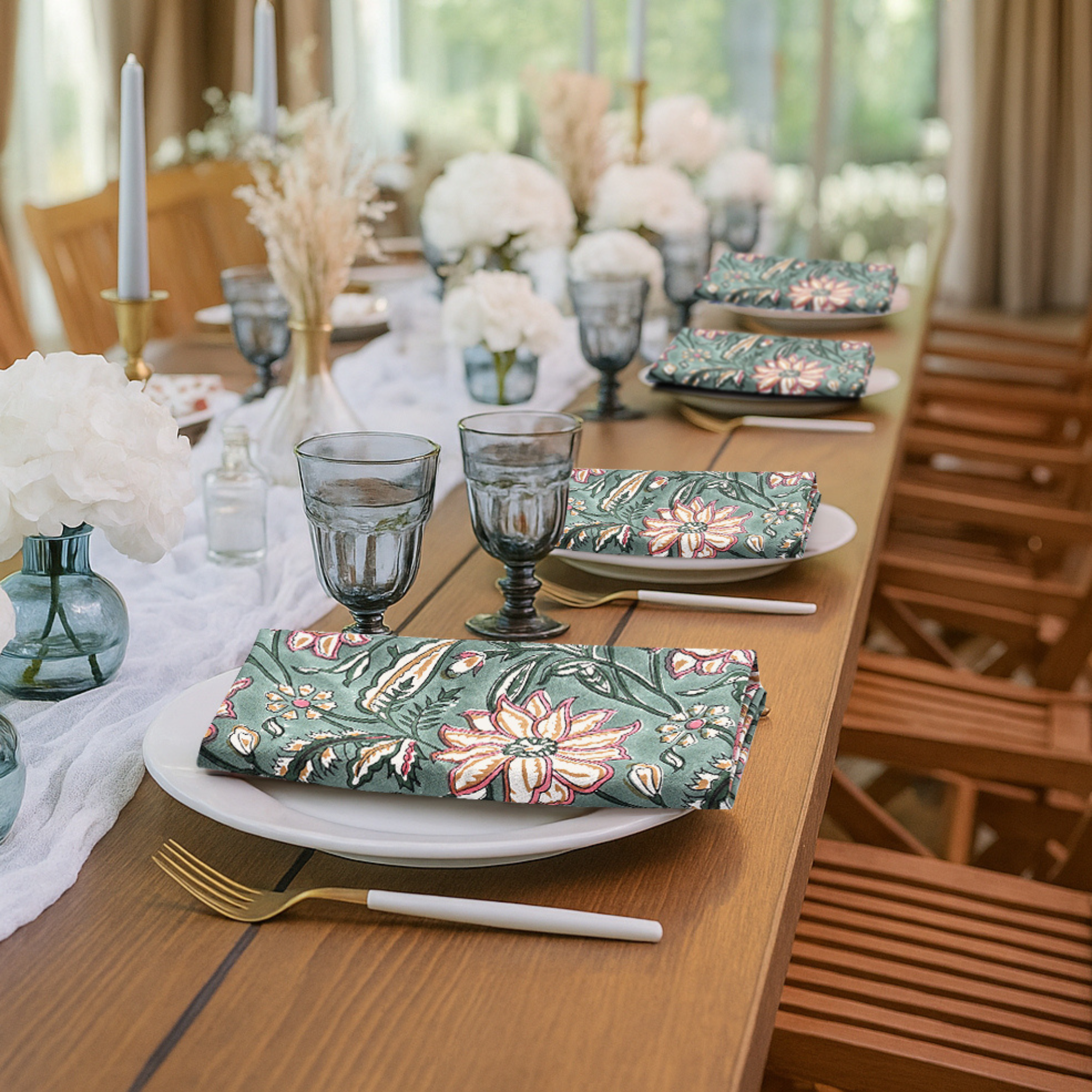 Dining table set with floral-patterned napkins and glasses, surrounded by chairs.