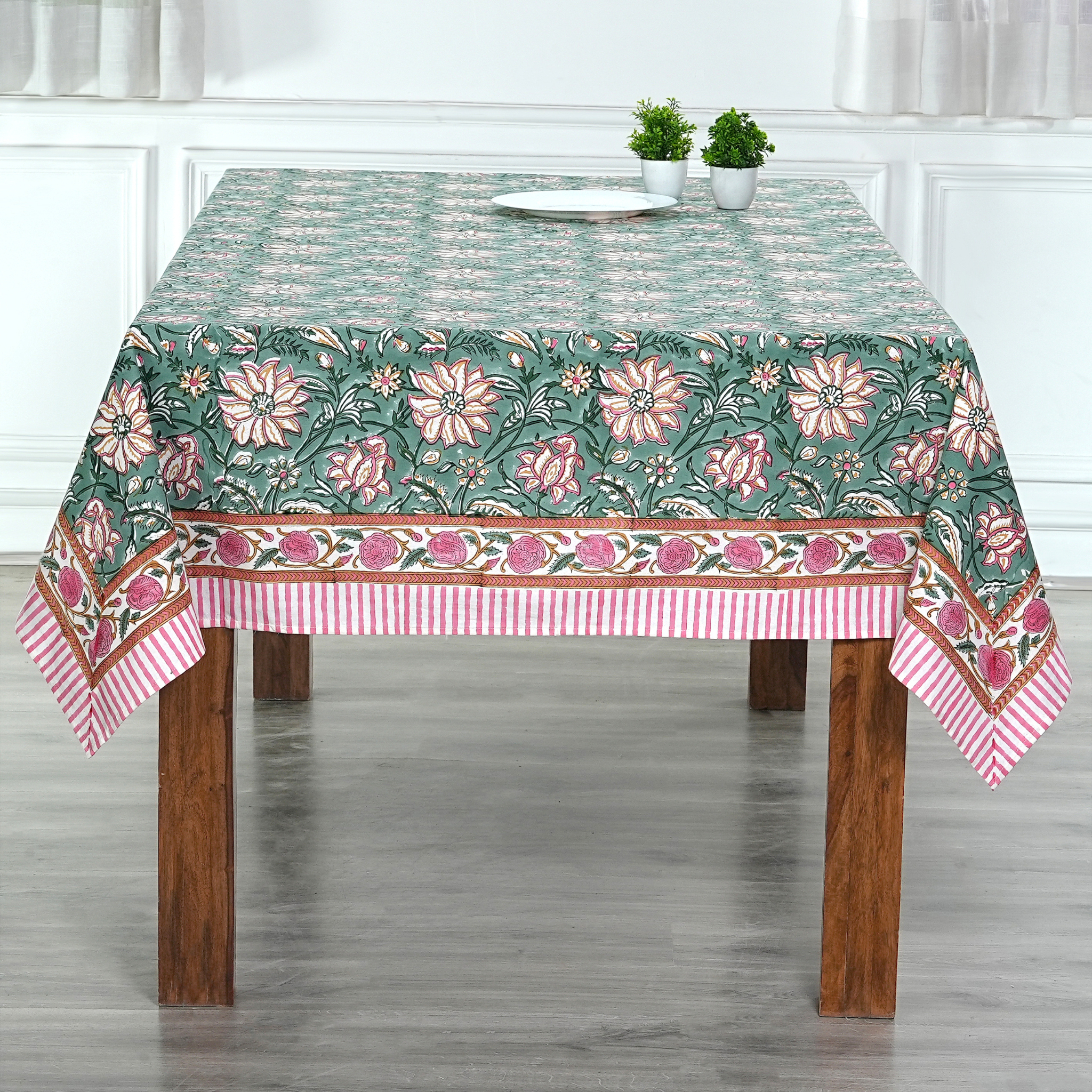 Floral patterned tablecloth on a wooden table with a white curtain background