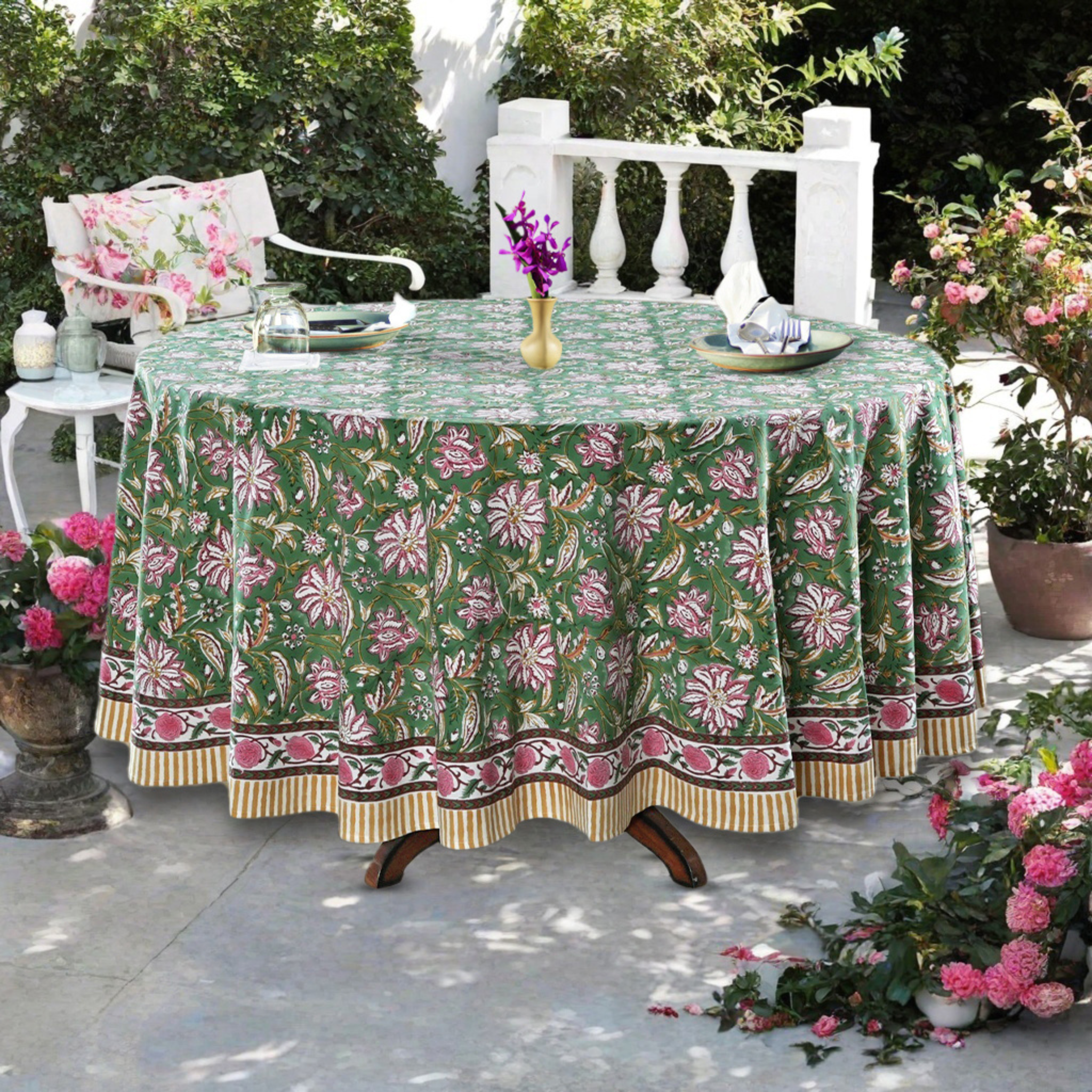 Outdoor table setting with a floral-patterned tablecloth, chairs, and decorative elements.