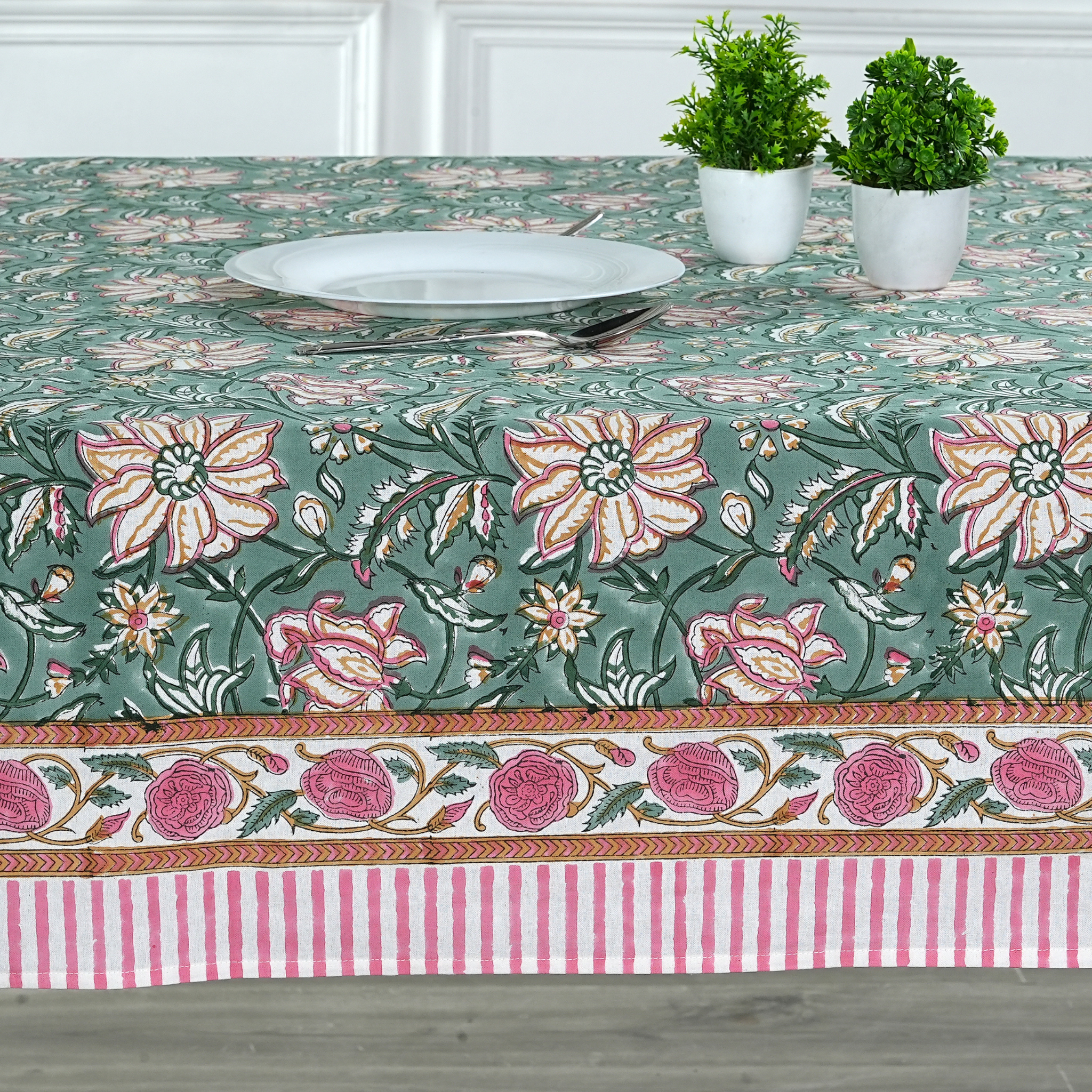 Floral patterned tablecloth with a striped border on a wooden table.