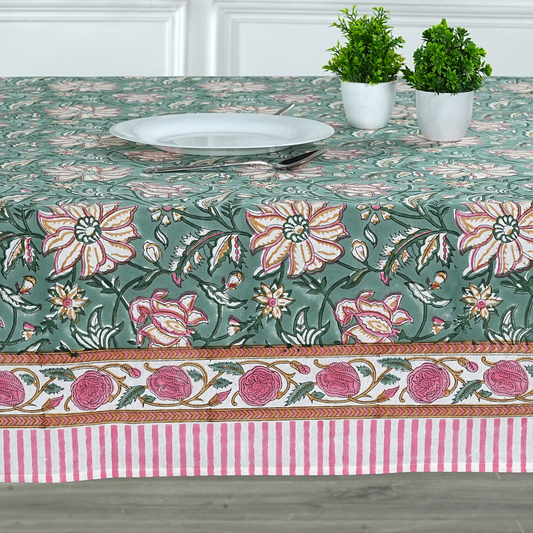 Floral patterned tablecloth with a striped border on a wooden table.