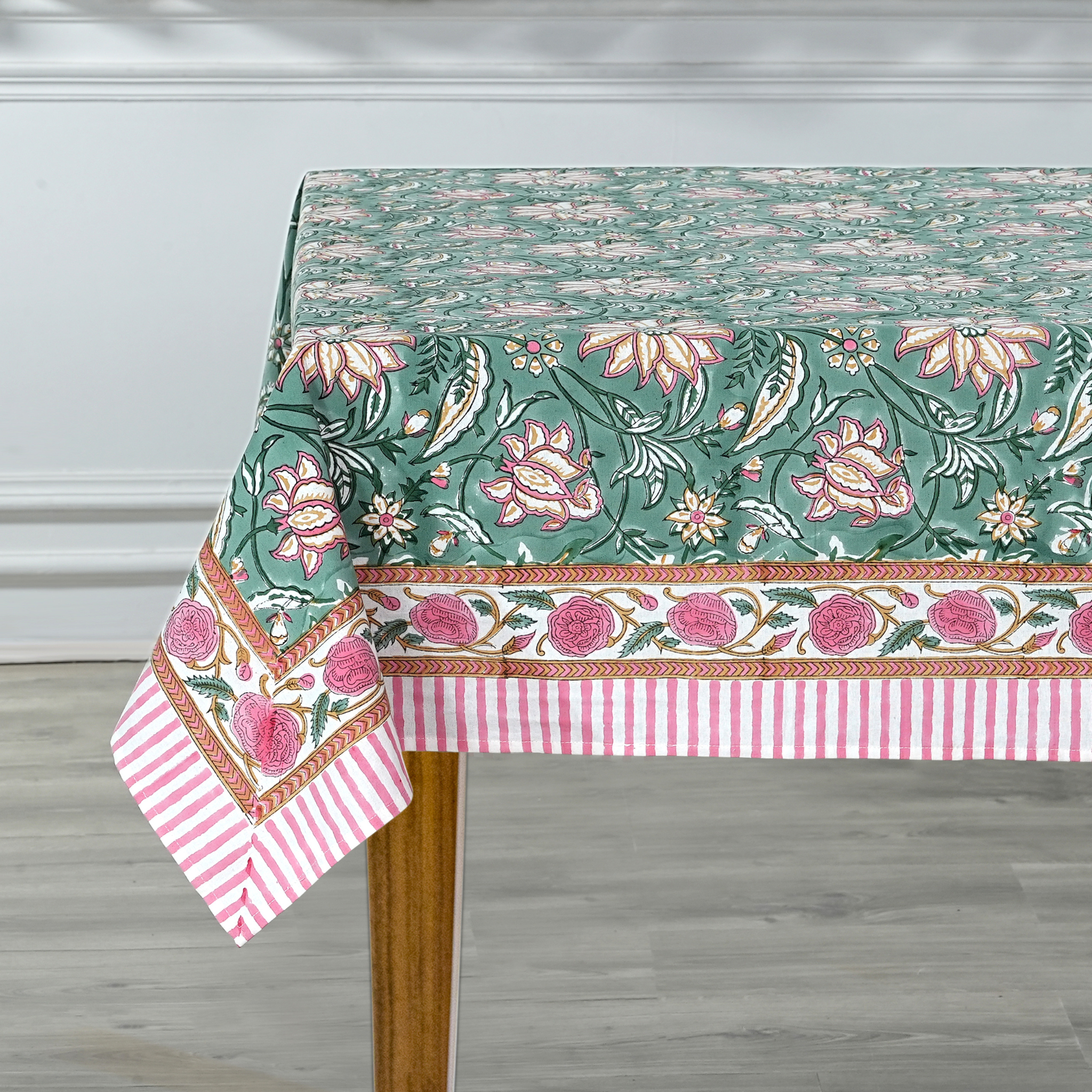 Floral patterned tablecloth on a wooden table with a white wall background