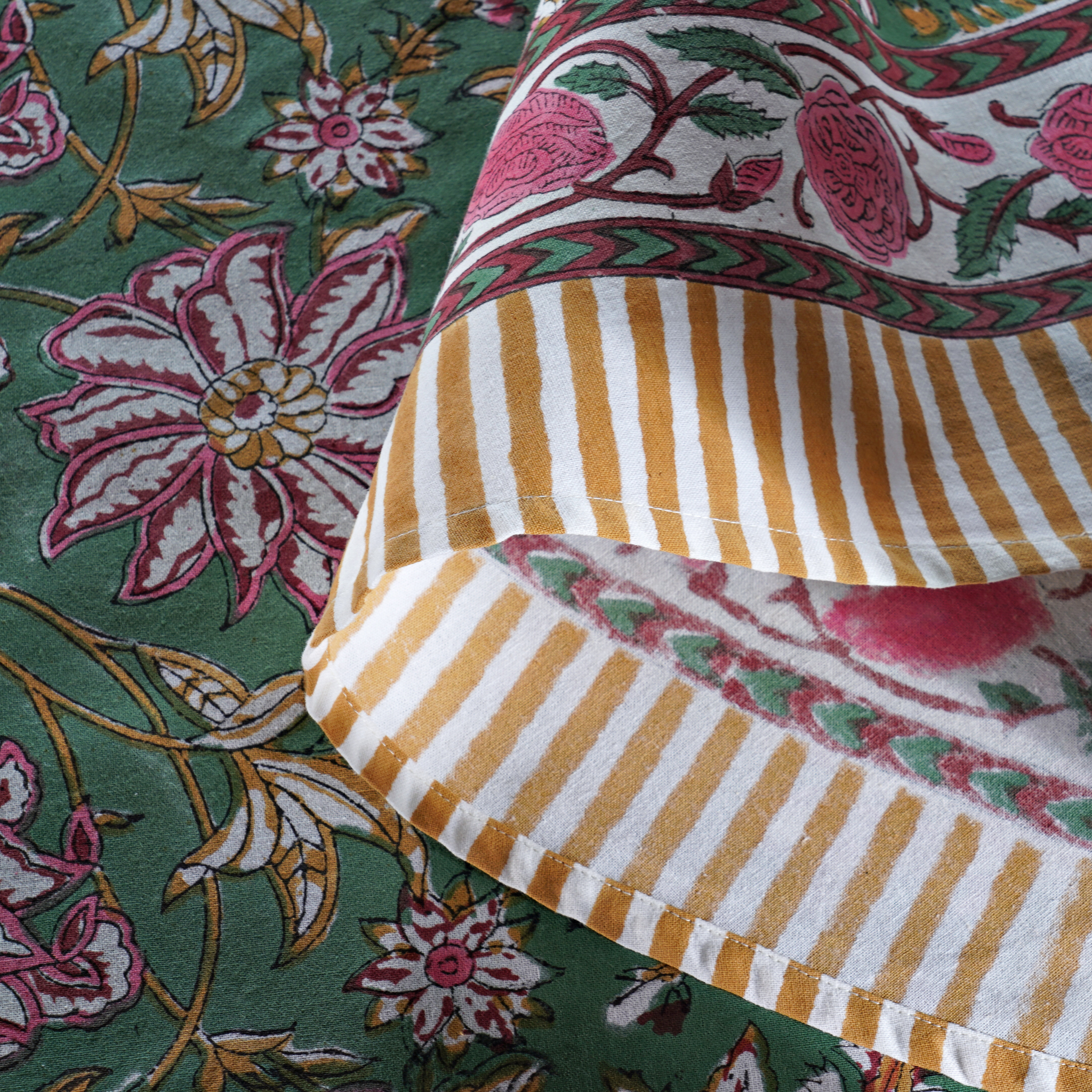 Close-up of patterned fabric with floral and striped designs on a green background
