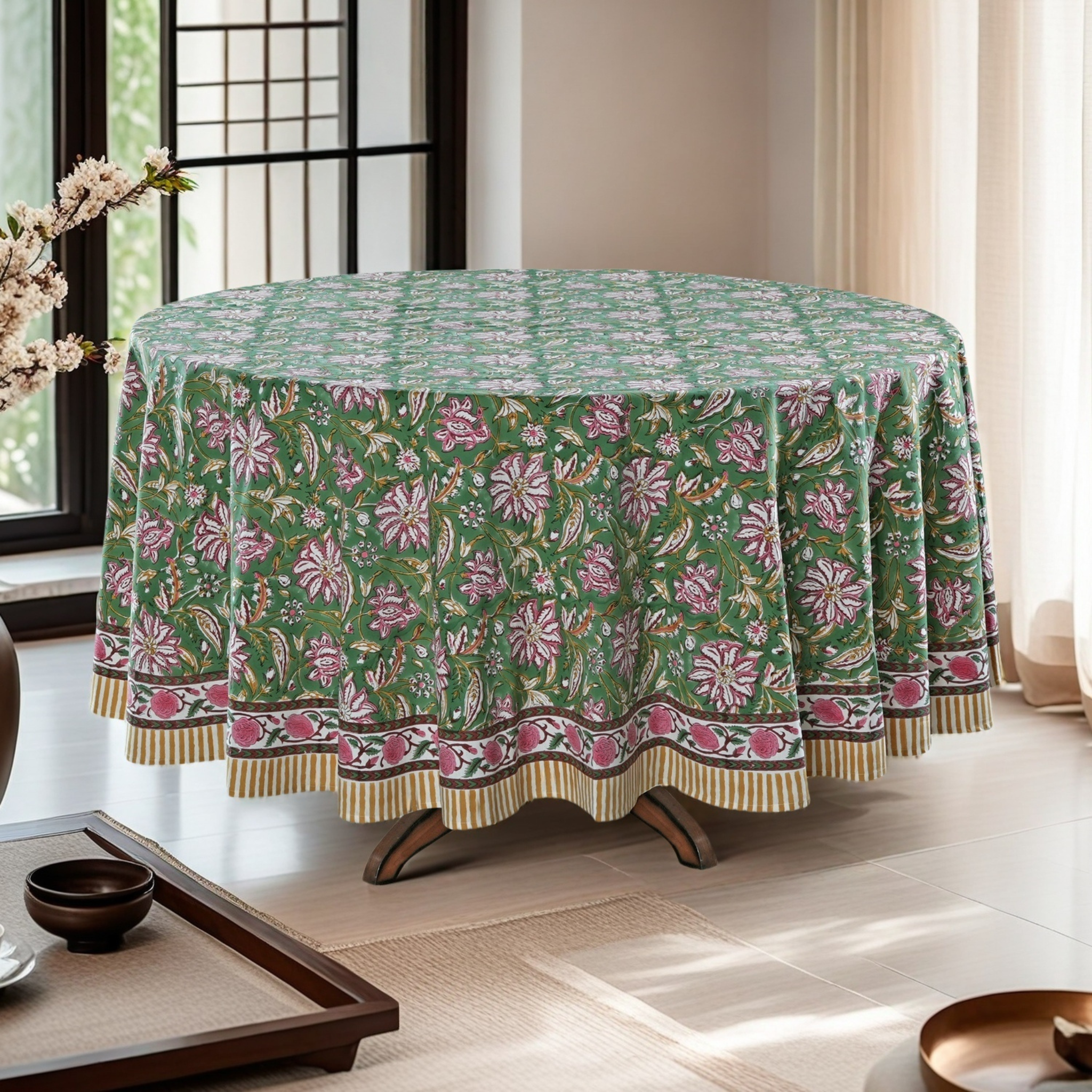Round table with a green floral patterned tablecloth in a bright room.