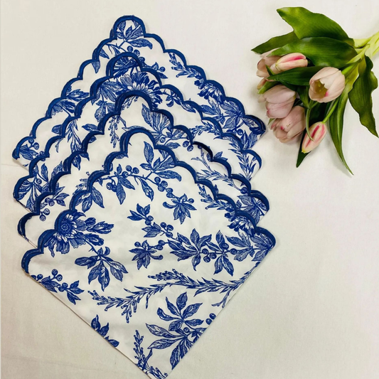 Set of blue floral placemats on a white surface with a bouquet of flowers.