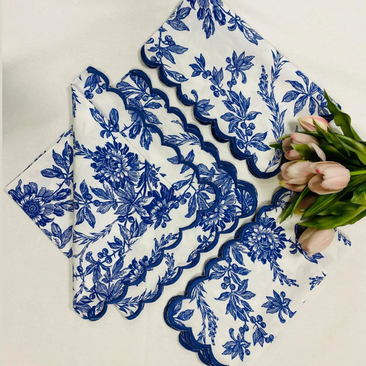 Set of blue floral lace doilies on a white surface with tulips.