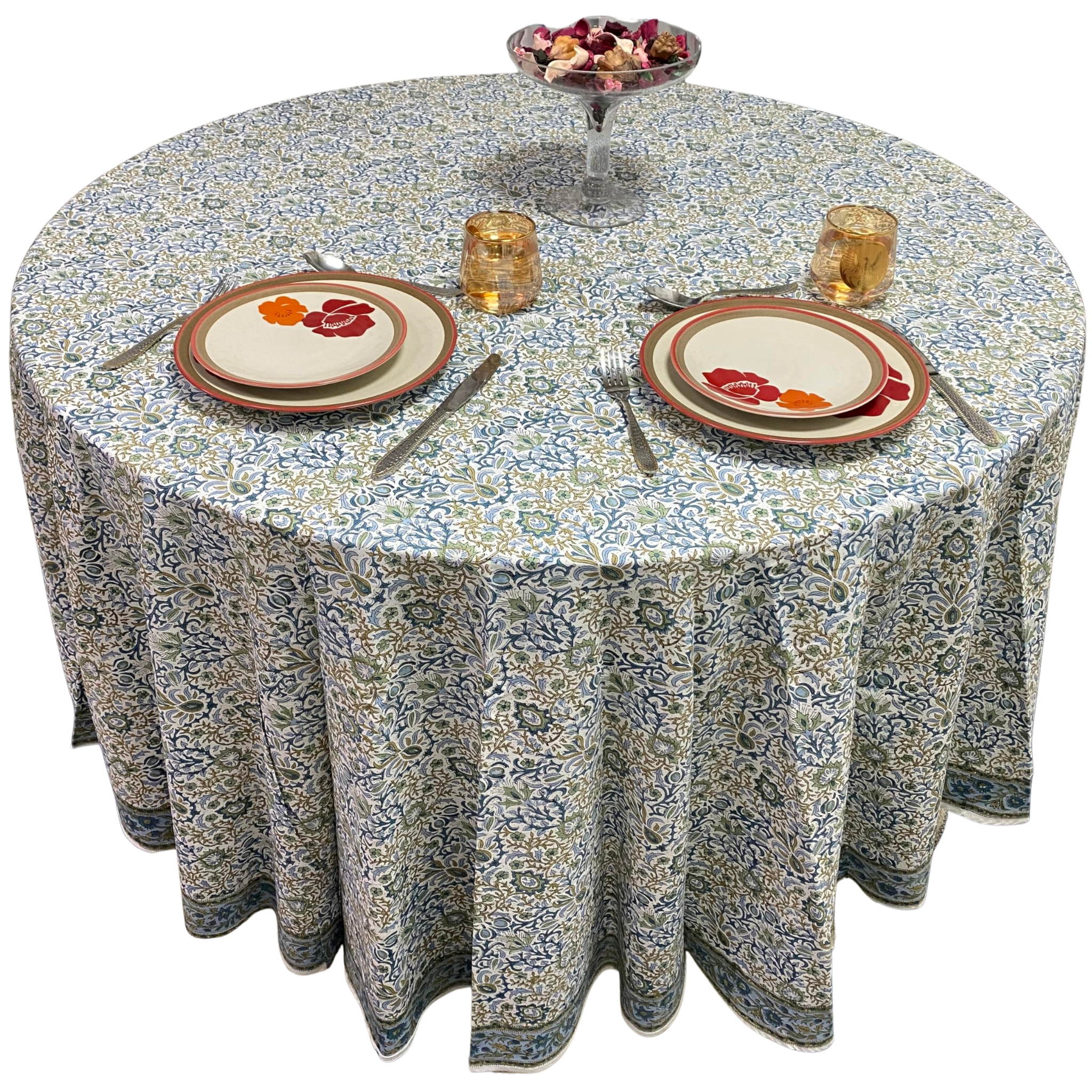 Round table with floral patterned tablecloth, plates, and glasses on a white background