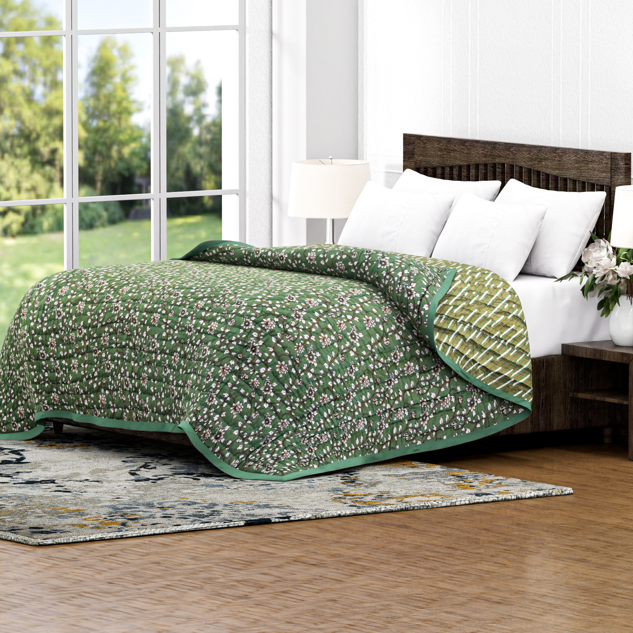 Green floral quilt on a bed in a bright room with large windows.