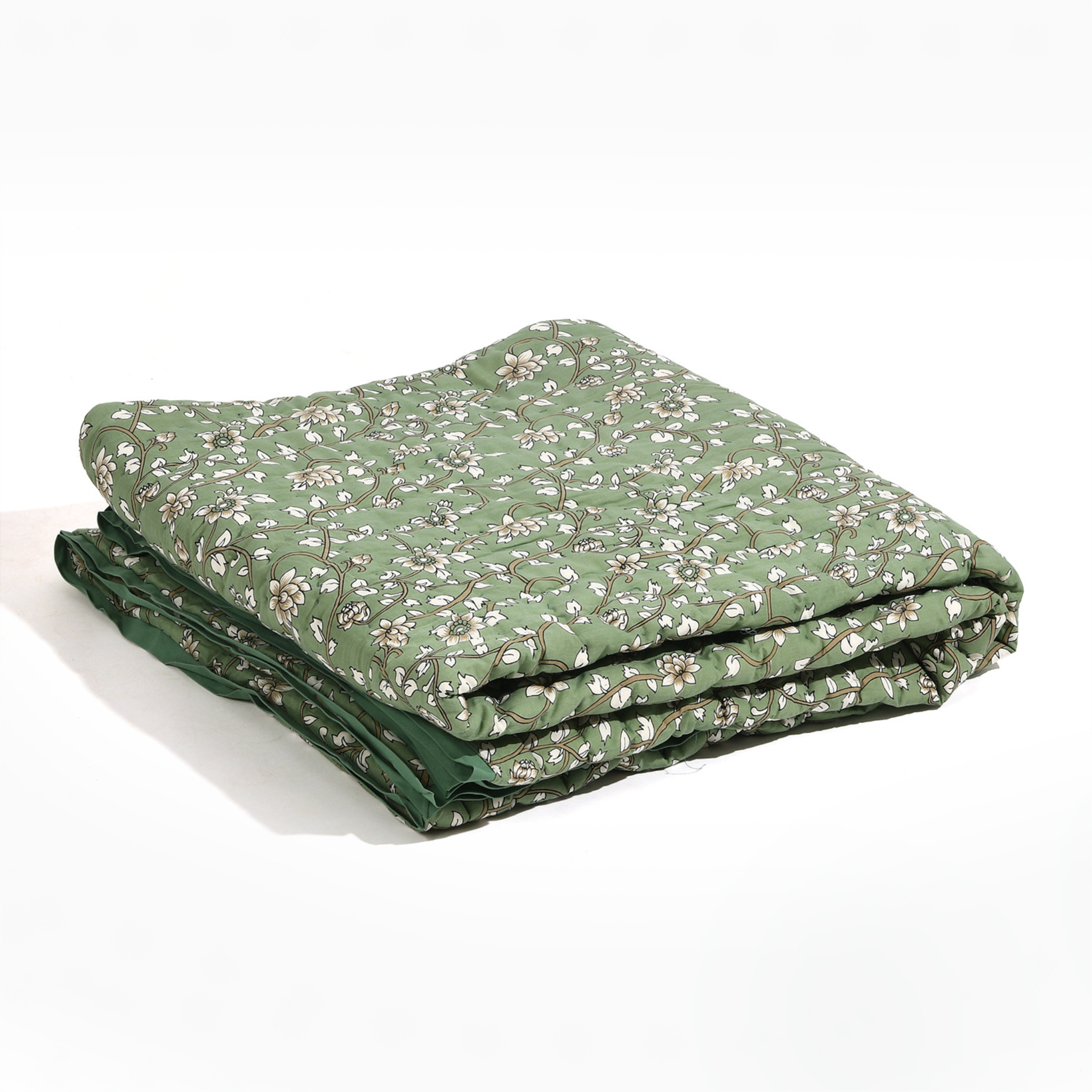 Folded green quilt with floral pattern on a white background