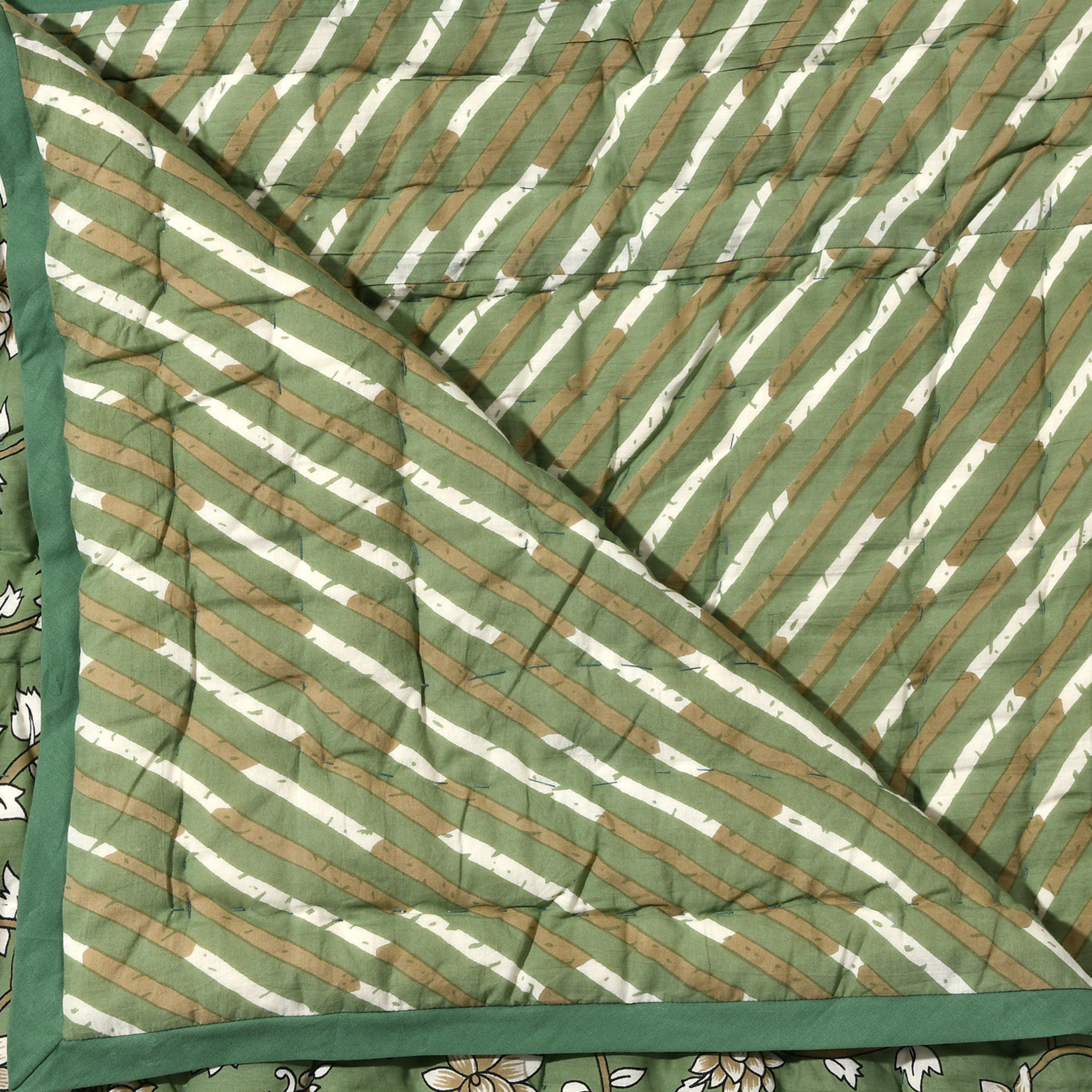 Green and white striped fabric with a floral pattern underneath