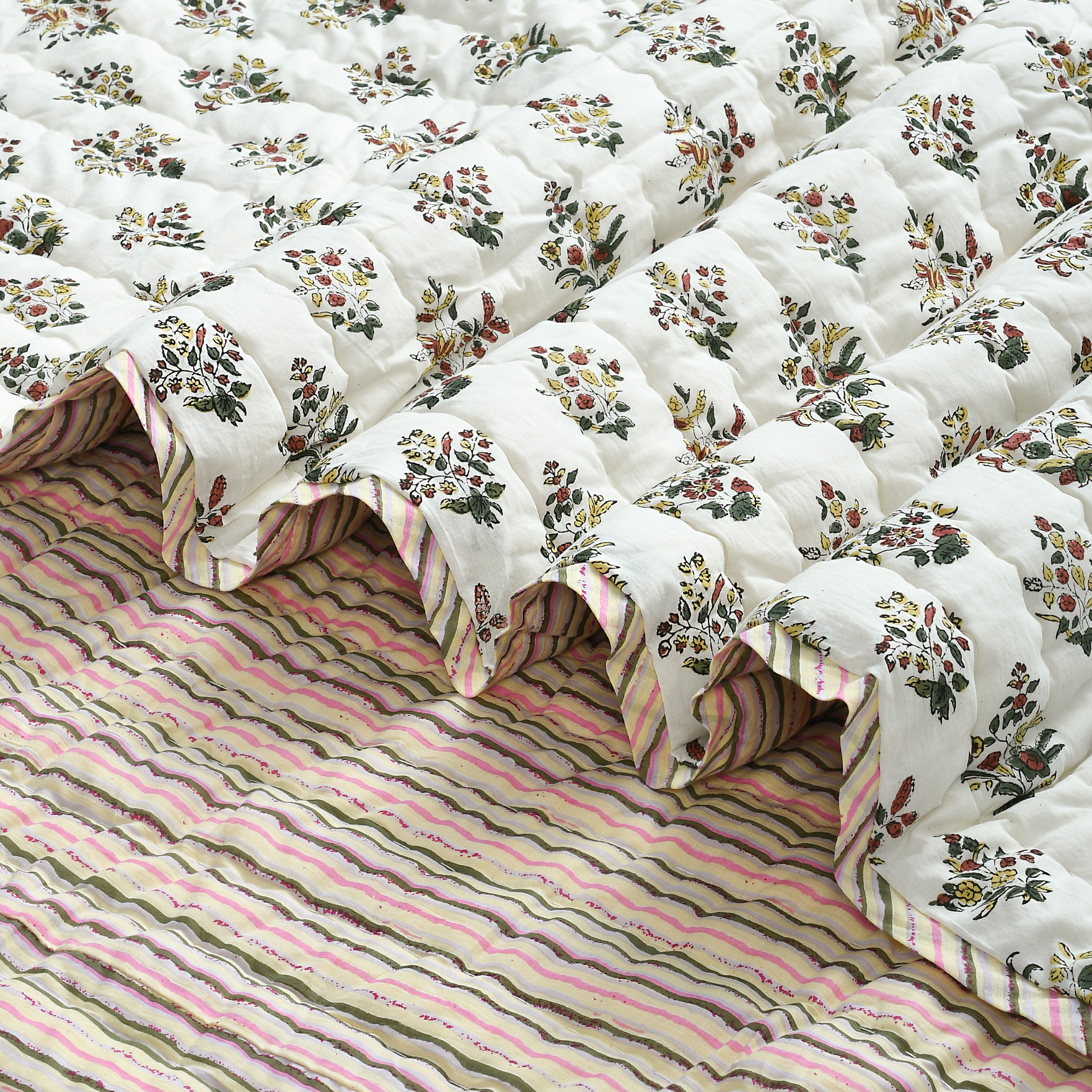 Floral-patterned quilt on a striped bedspread