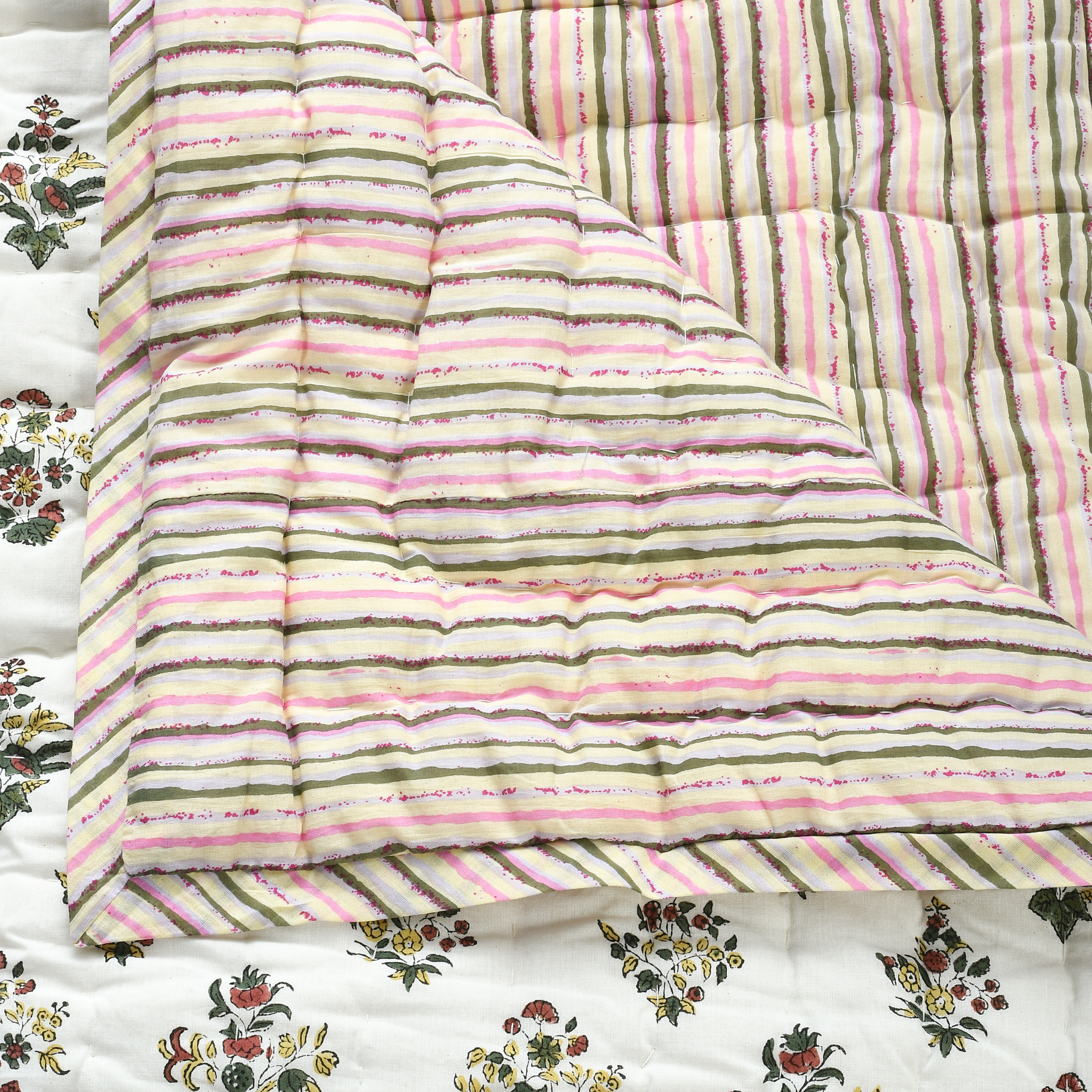 Striped quilt with pink and green pattern on floral fabric background
