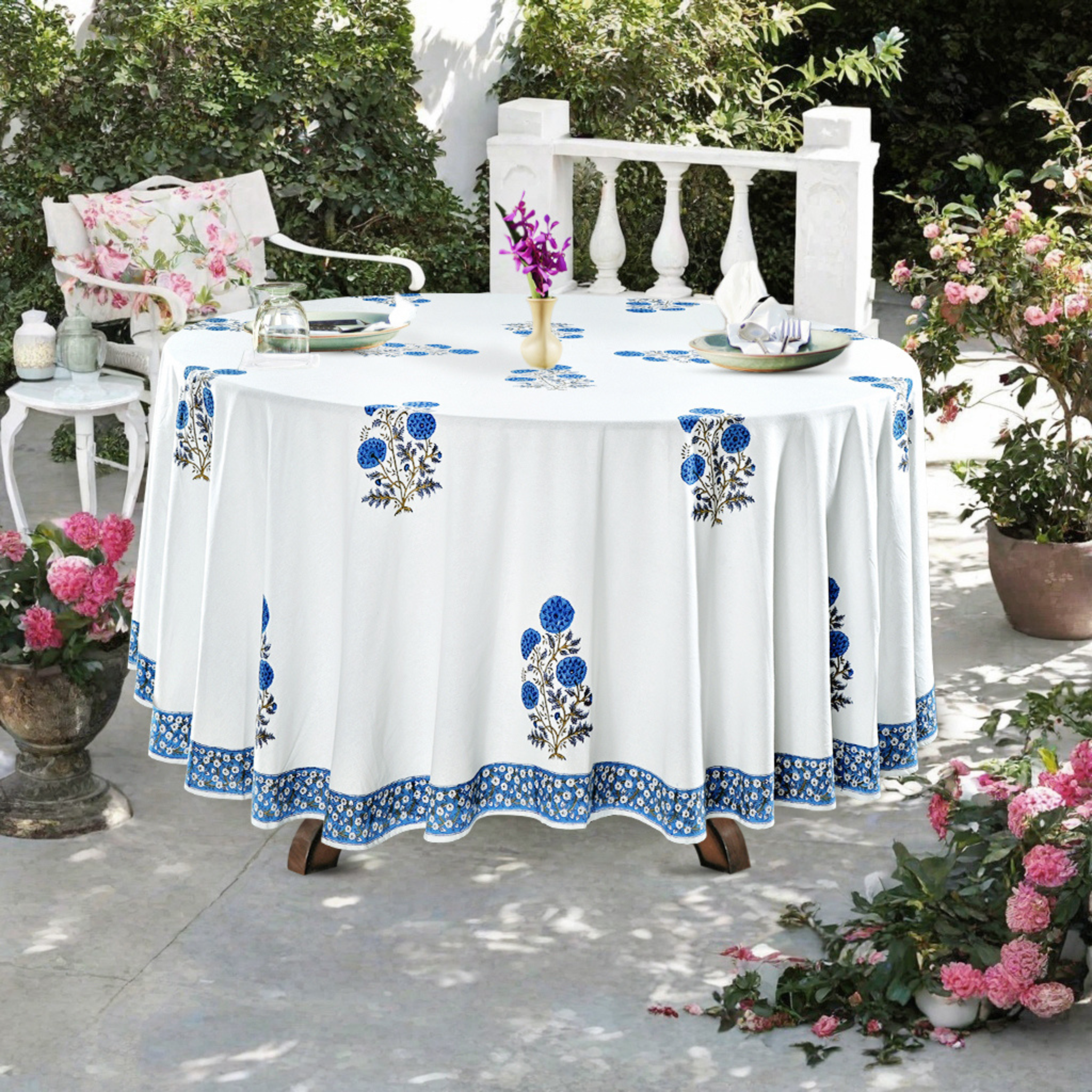 Outdoor table setting with a floral tablecloth and decorative elements.