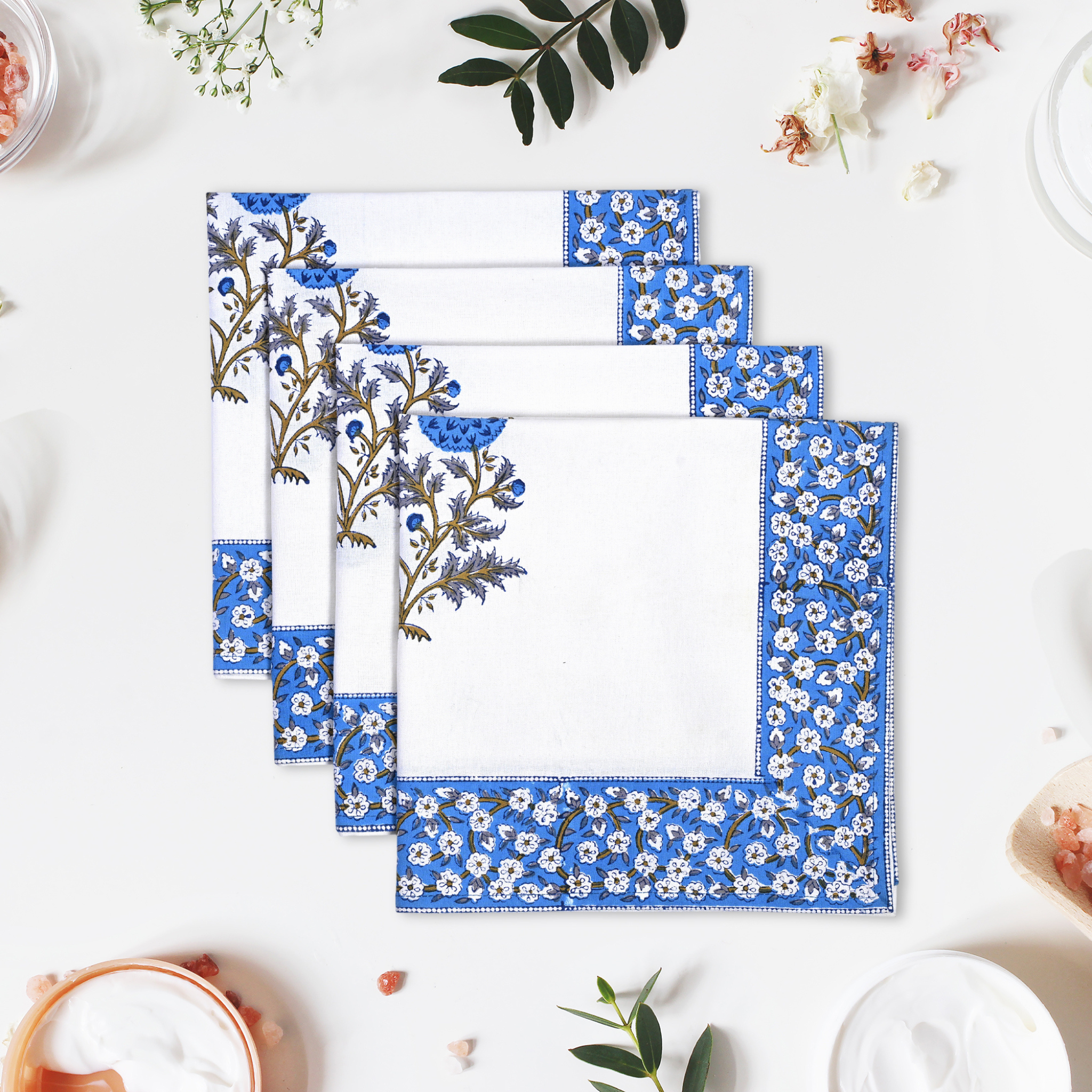 Set of four blue floral placemats on a white surface with decorative elements.