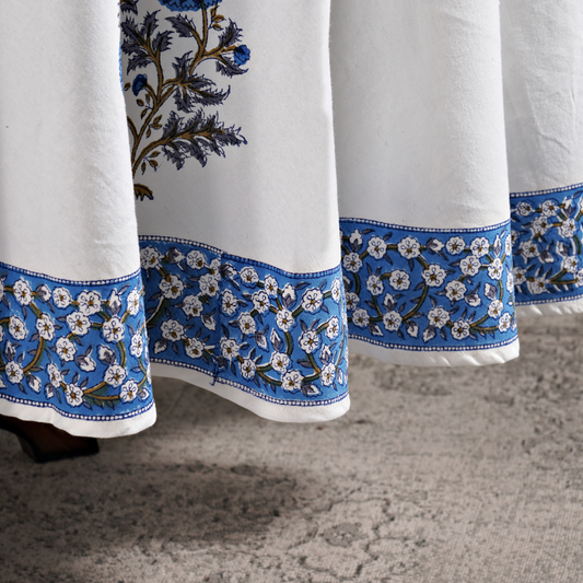 White curtains with blue floral embroidery on a textured floor.