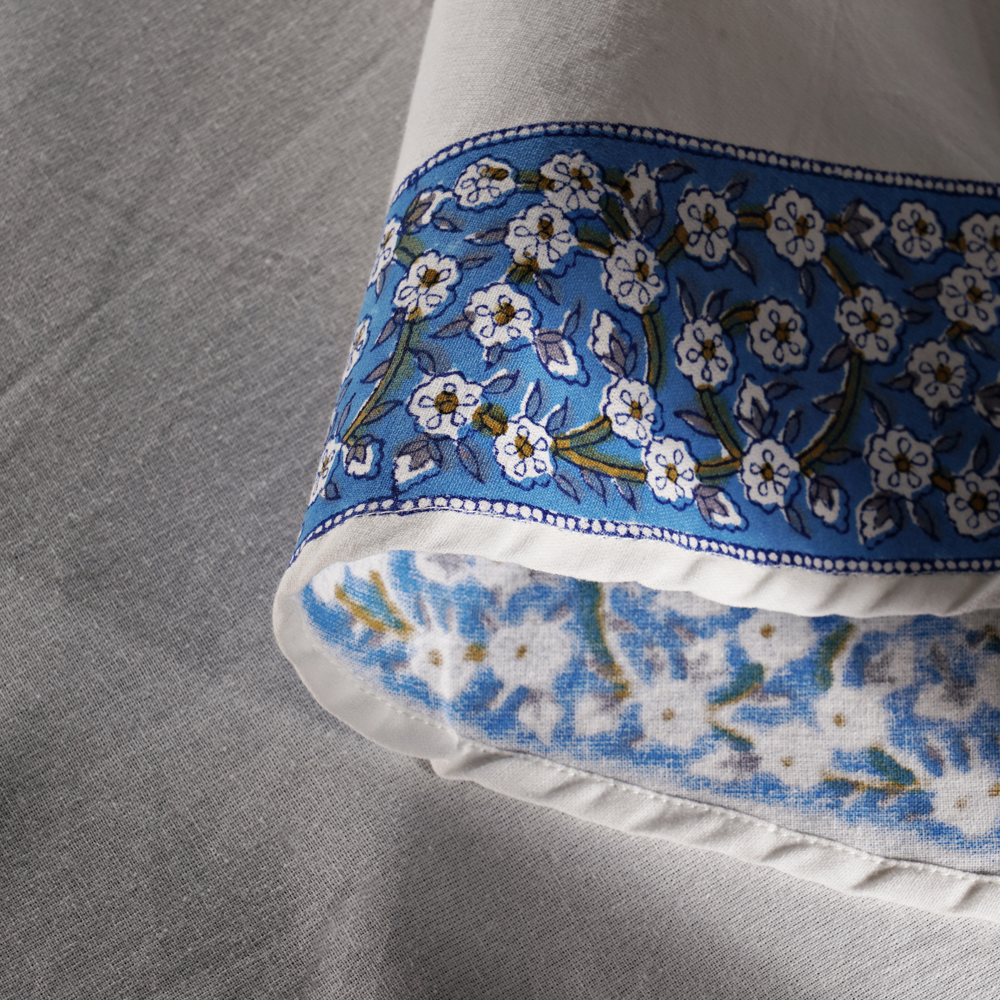 Close-up of a pillow with blue floral pattern on a gray fabric background