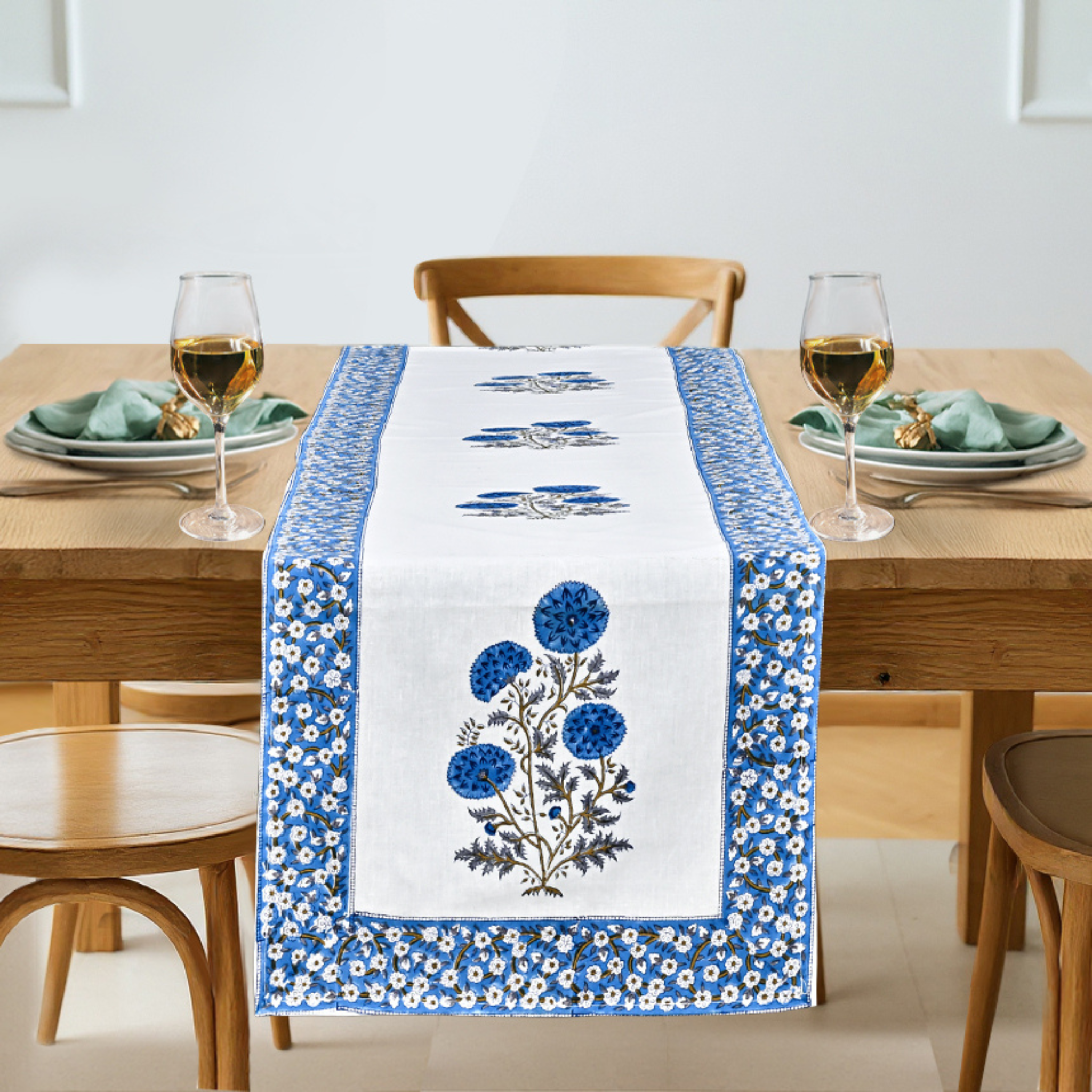 Dining table set with a floral embroidered table runner, glasses, and plates.
