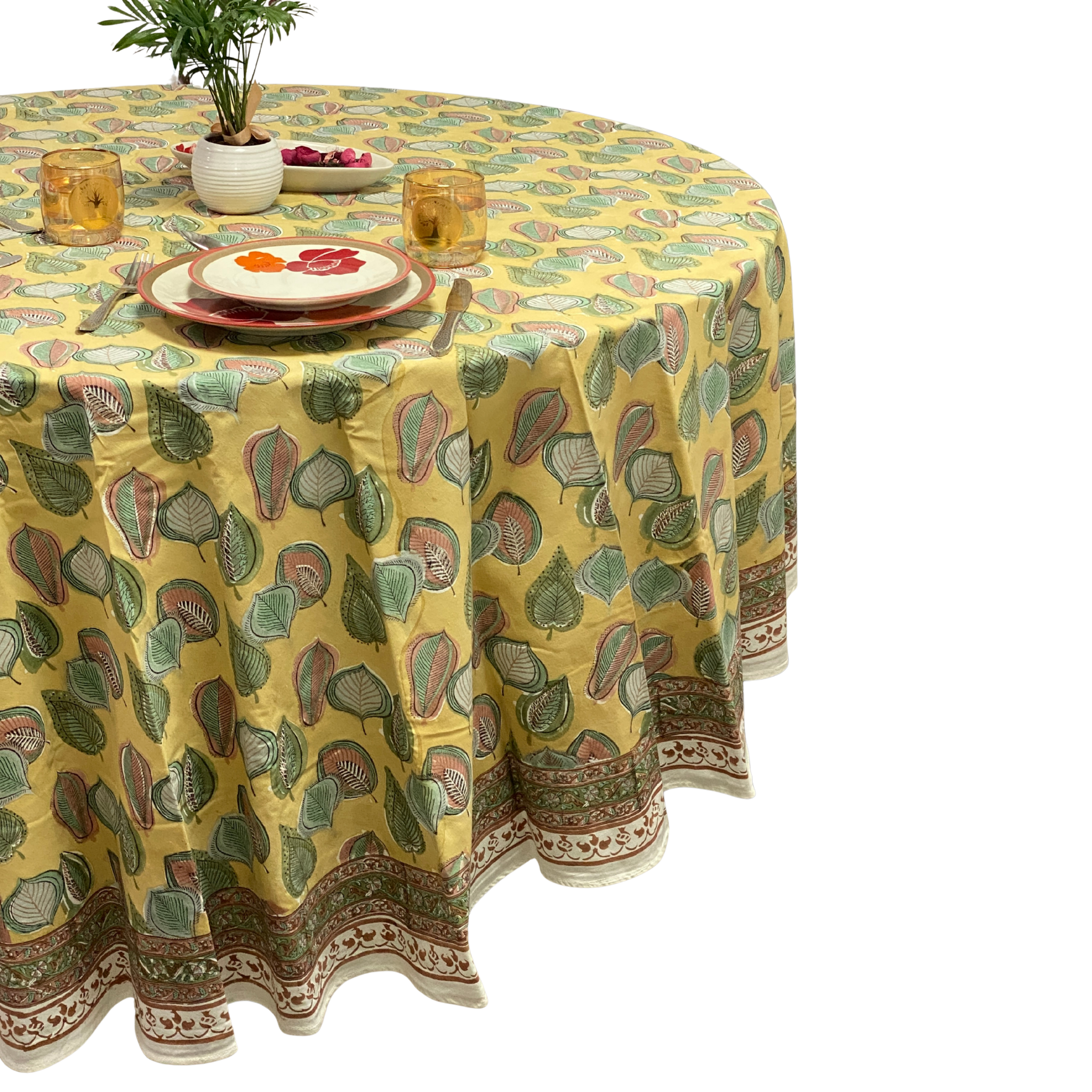 Round table with a yellow patterned tablecloth on a white background