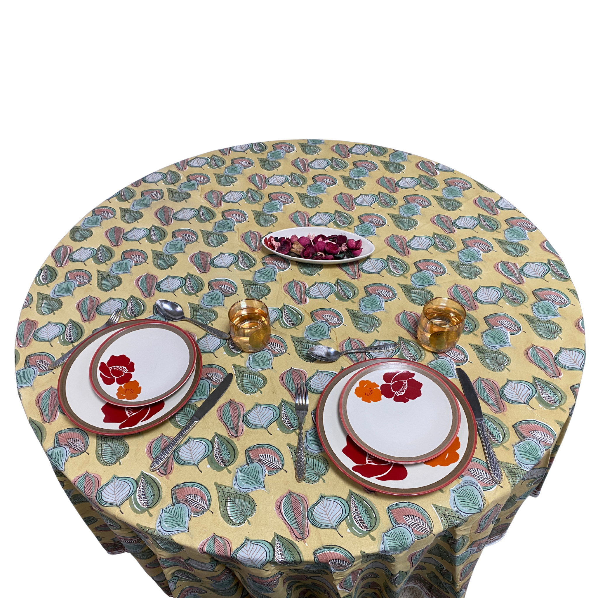 Round table with a patterned tablecloth set for a meal.