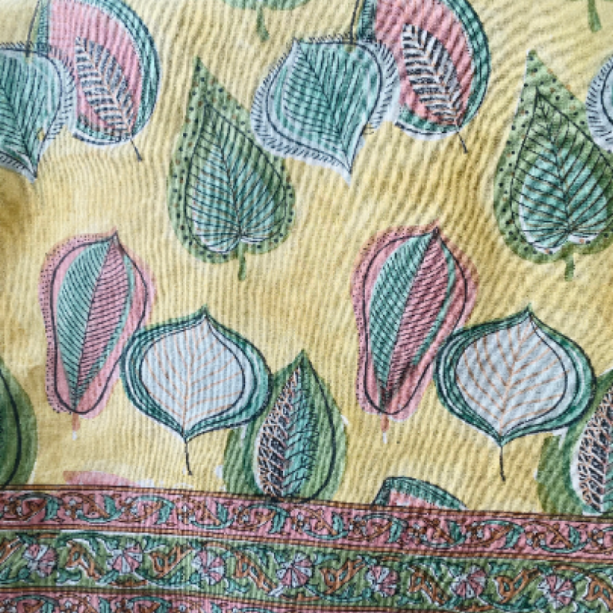 Textile with leaf pattern and decorative border on a yellow background
