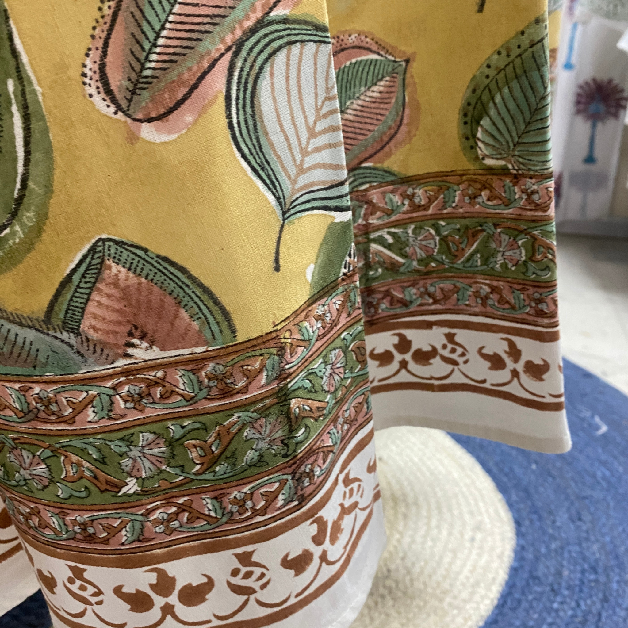 Close-up of a patterned fabric with intricate designs on a yellow background.