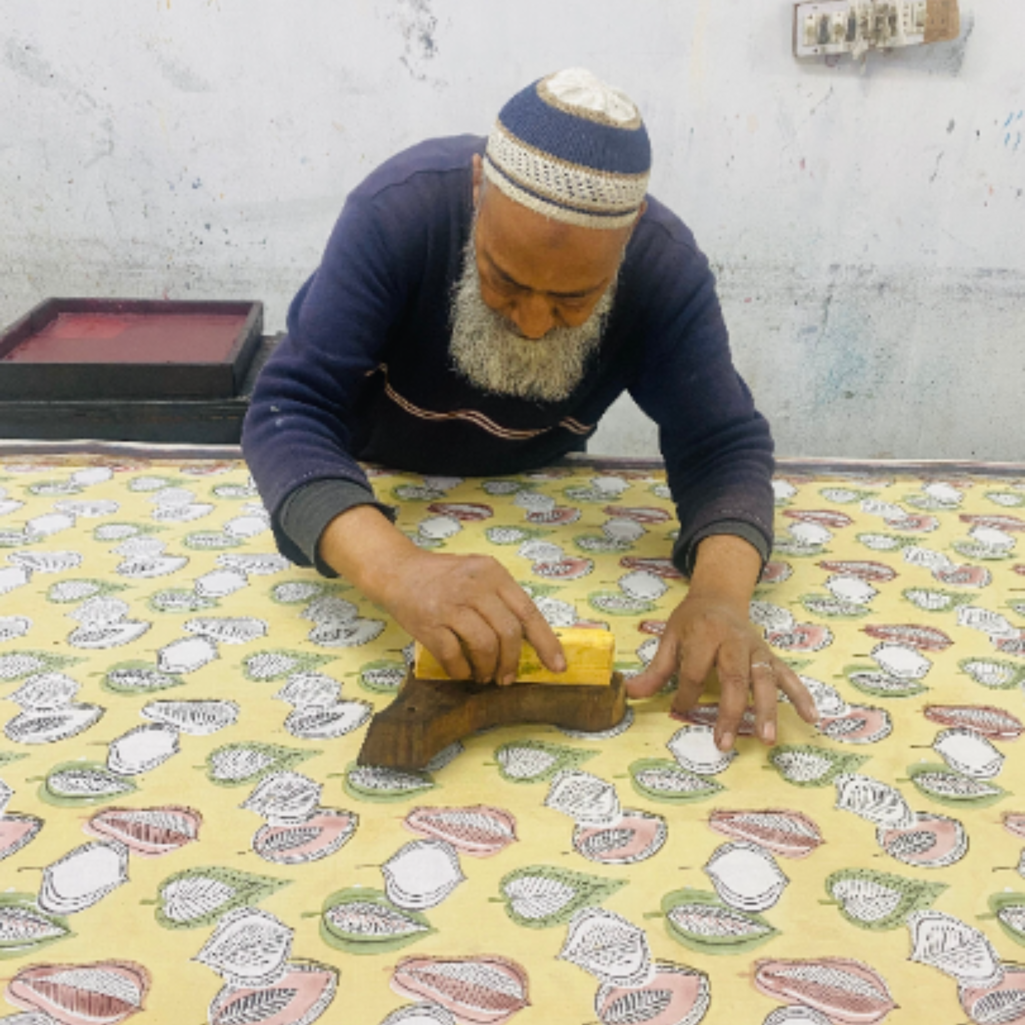 Man working on a piece of fabric with a pattern, using a tool.