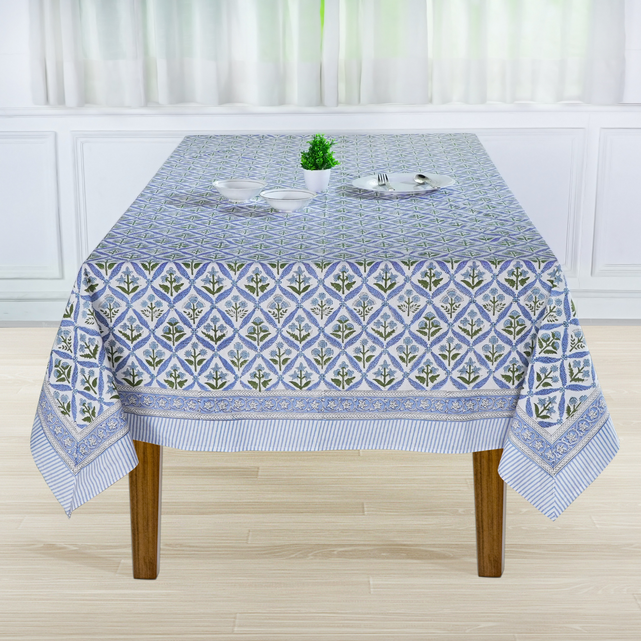 Tablecloth with geometric pattern on a wooden table in a room with white curtains.