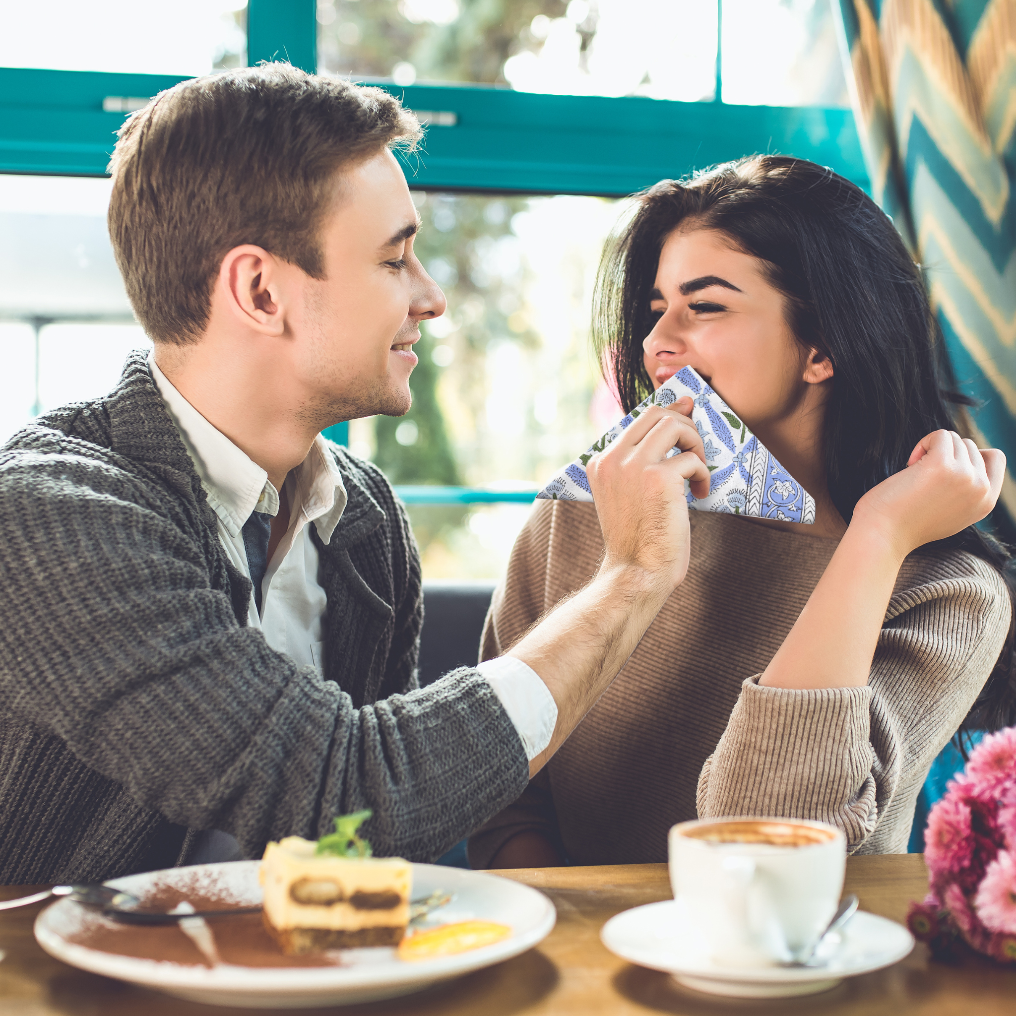 Man and woman sharing a moment at a cafe with a plate of food and coffee.
