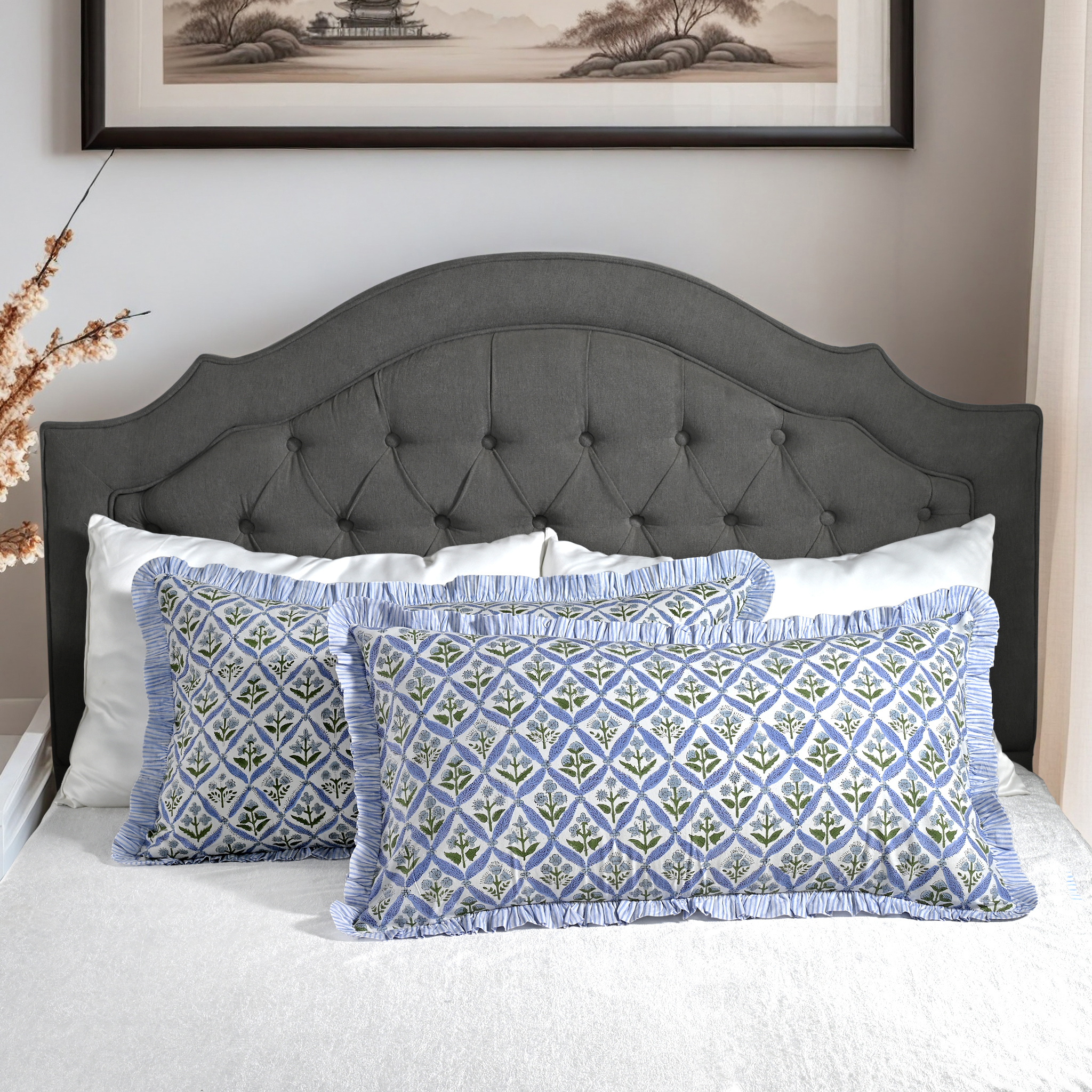 Large block print cotton pillows styled on gray upholstered bed.