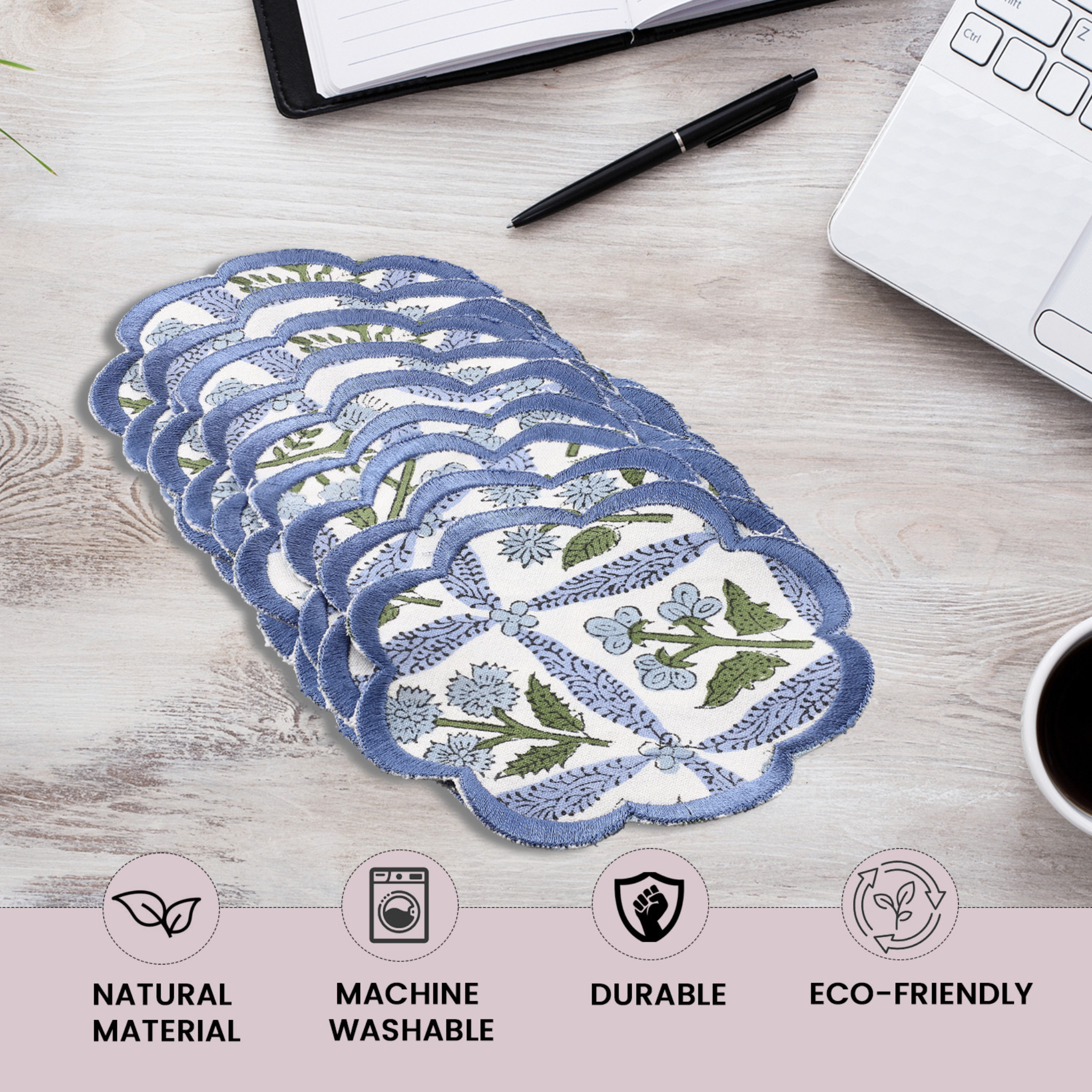 Set of reusable menstrual pads with floral design on a desk with office supplies.