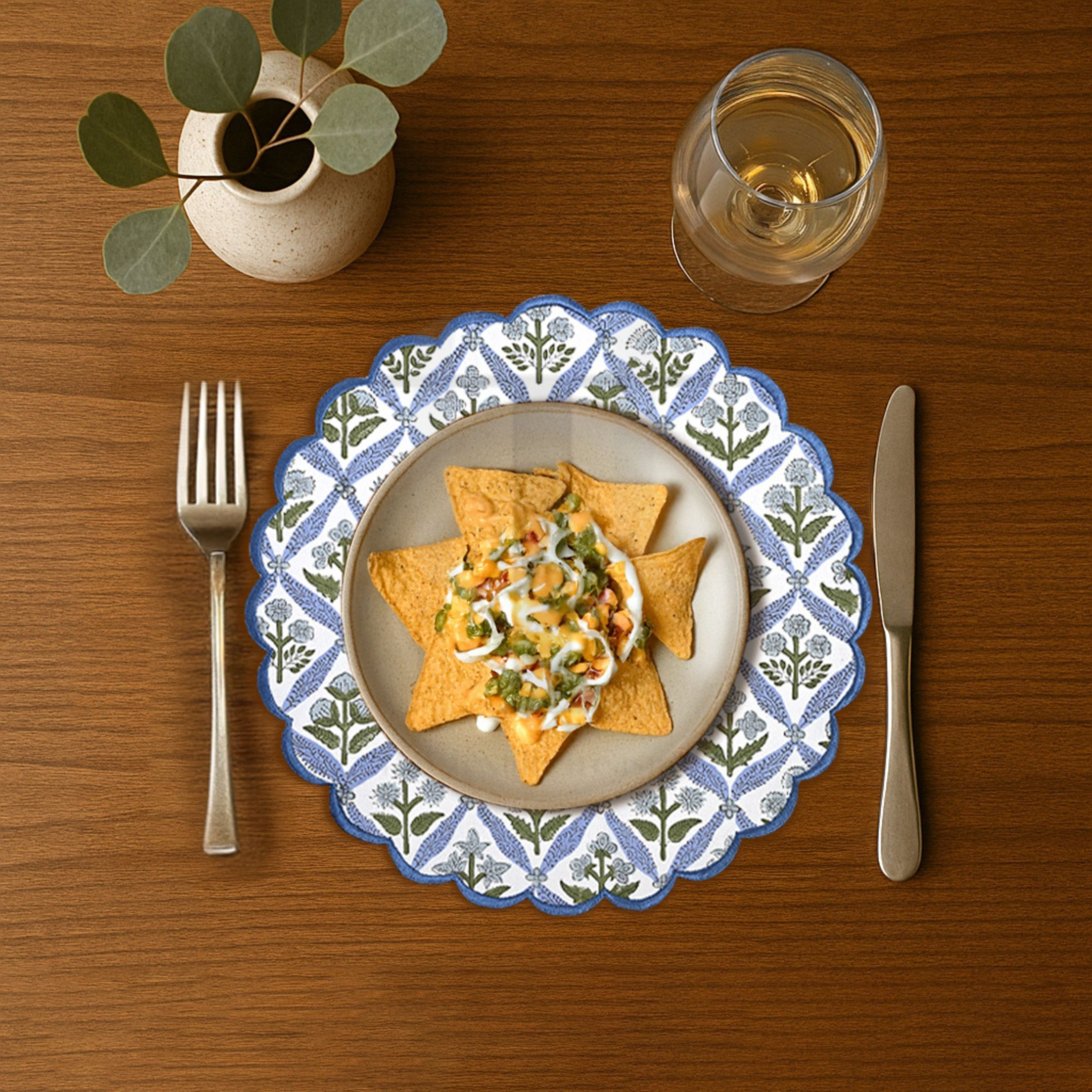 Dinner setting with a plate of food, fork, knife, and glass on a wooden table.