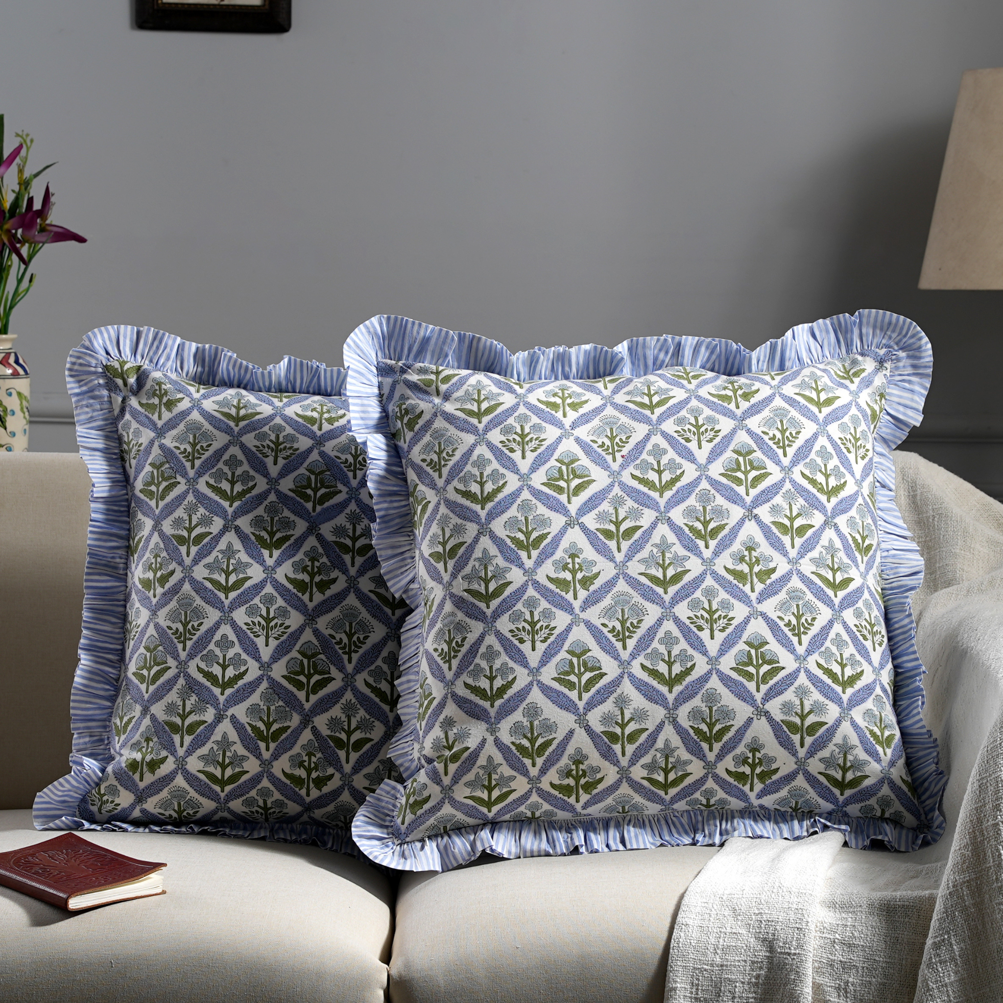 Two patterned pillows on a sofa with a neutral background
