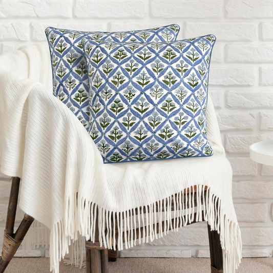 Decorative pillow with geometric pattern on a white chair against a white brick wall.