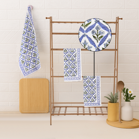 Set of blue and white patterned towels on a rack against a tiled wall.