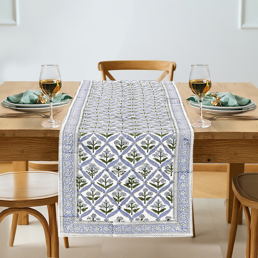Dining table set with a patterned table runner, glasses, and plates.