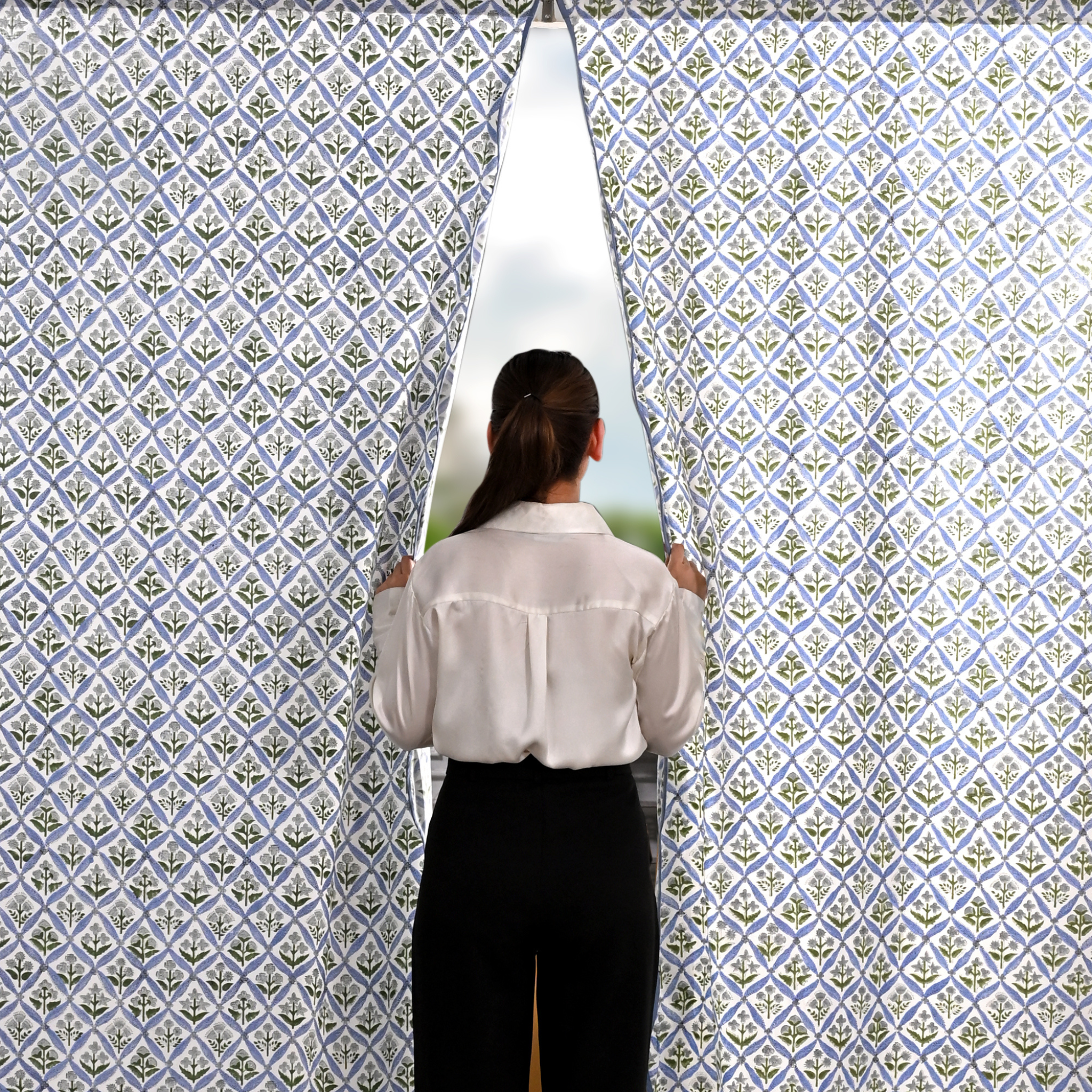 Person standing in front of a patterned wall with a window showing a scenic view.