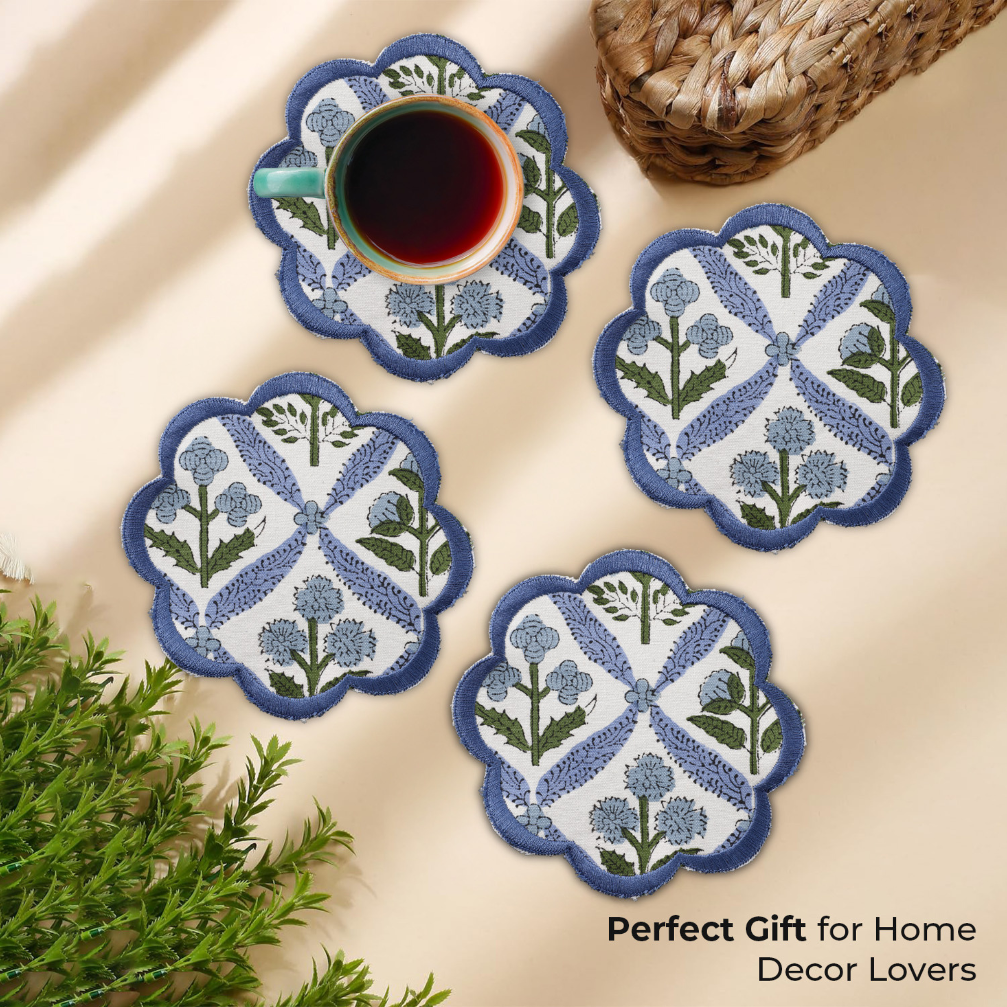 Set of four decorative coasters with floral patterns on a beige surface, accompanied by a cup of coffee.