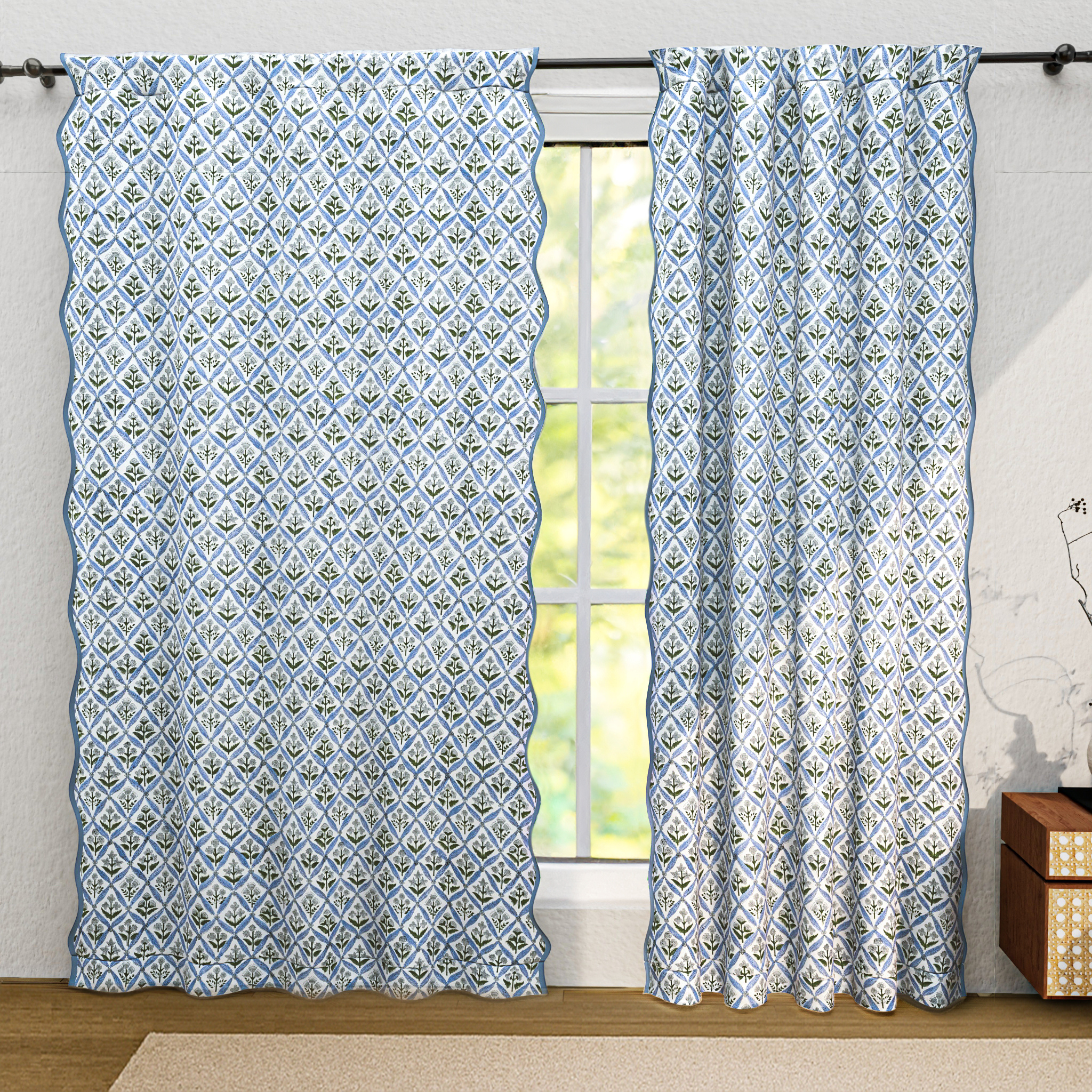 Patterned curtains hanging in front of a window with a neutral background