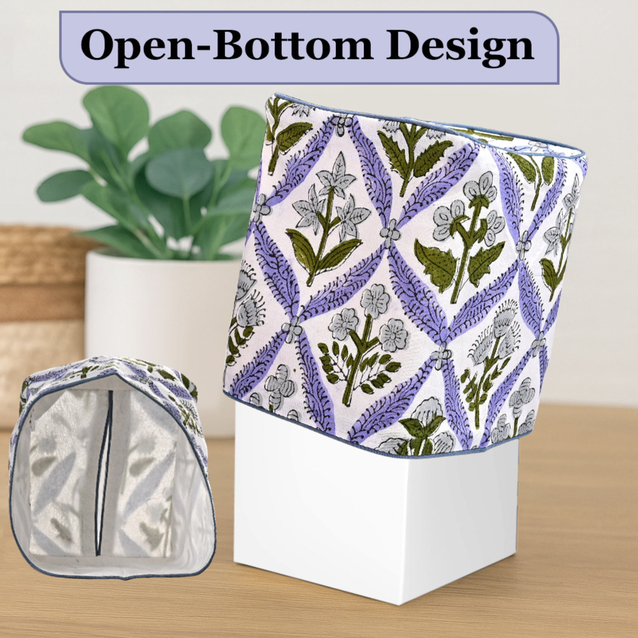 Floral-patterned fabric with open-bottom design on a white box, plant in the background.