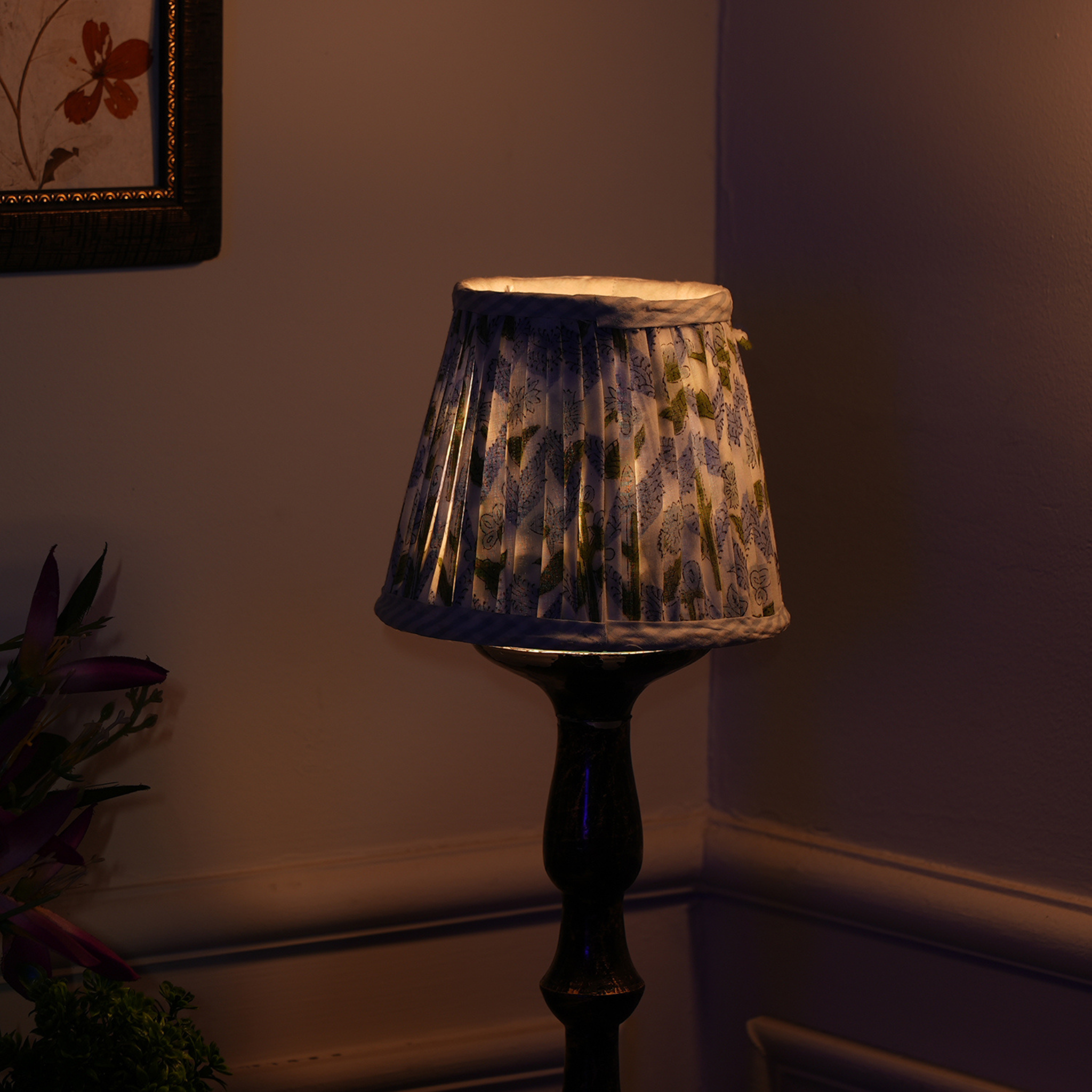 Decorative lamp with a patterned shade in a dimly lit room.