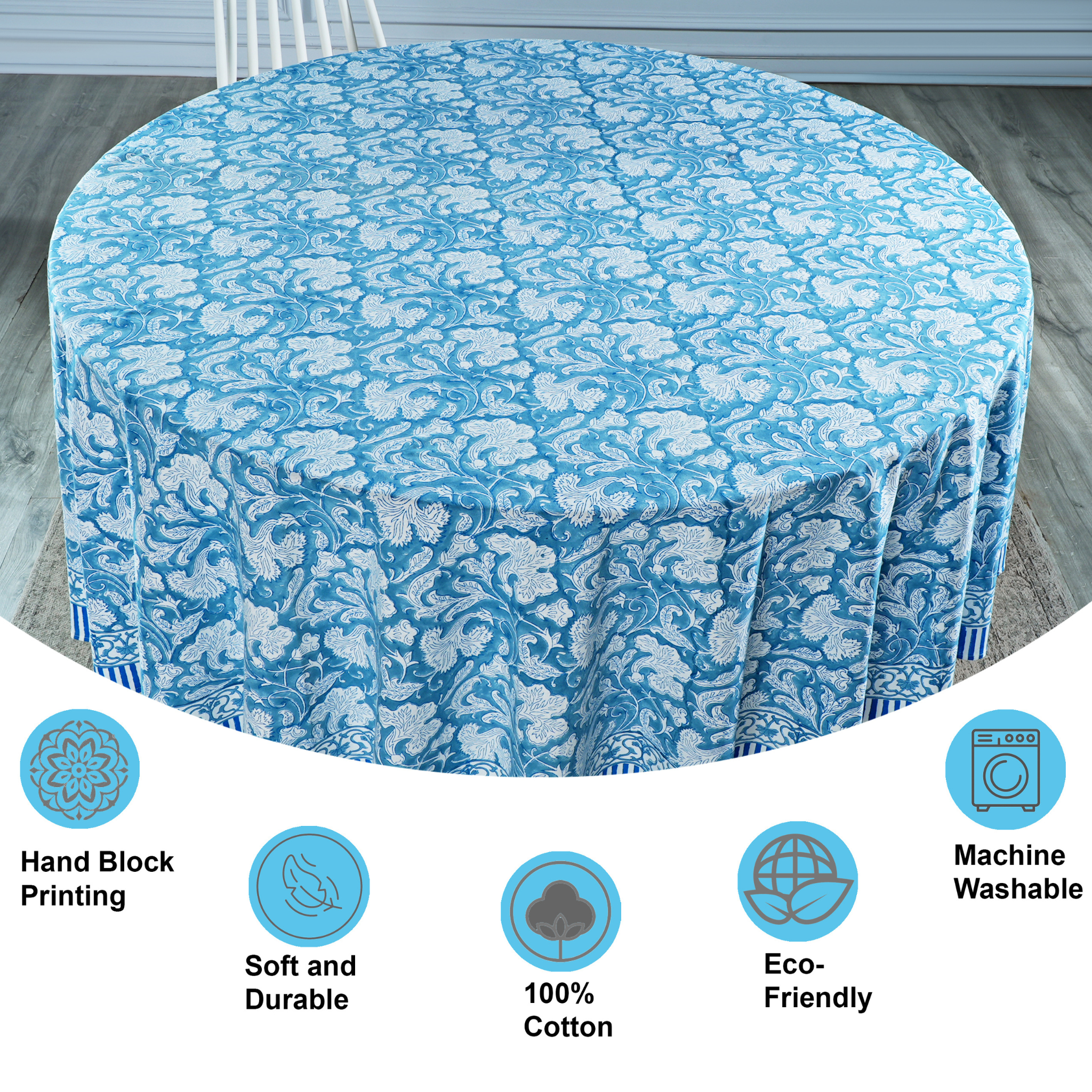 Round table covered with a blue floral tablecloth on a wooden floor.