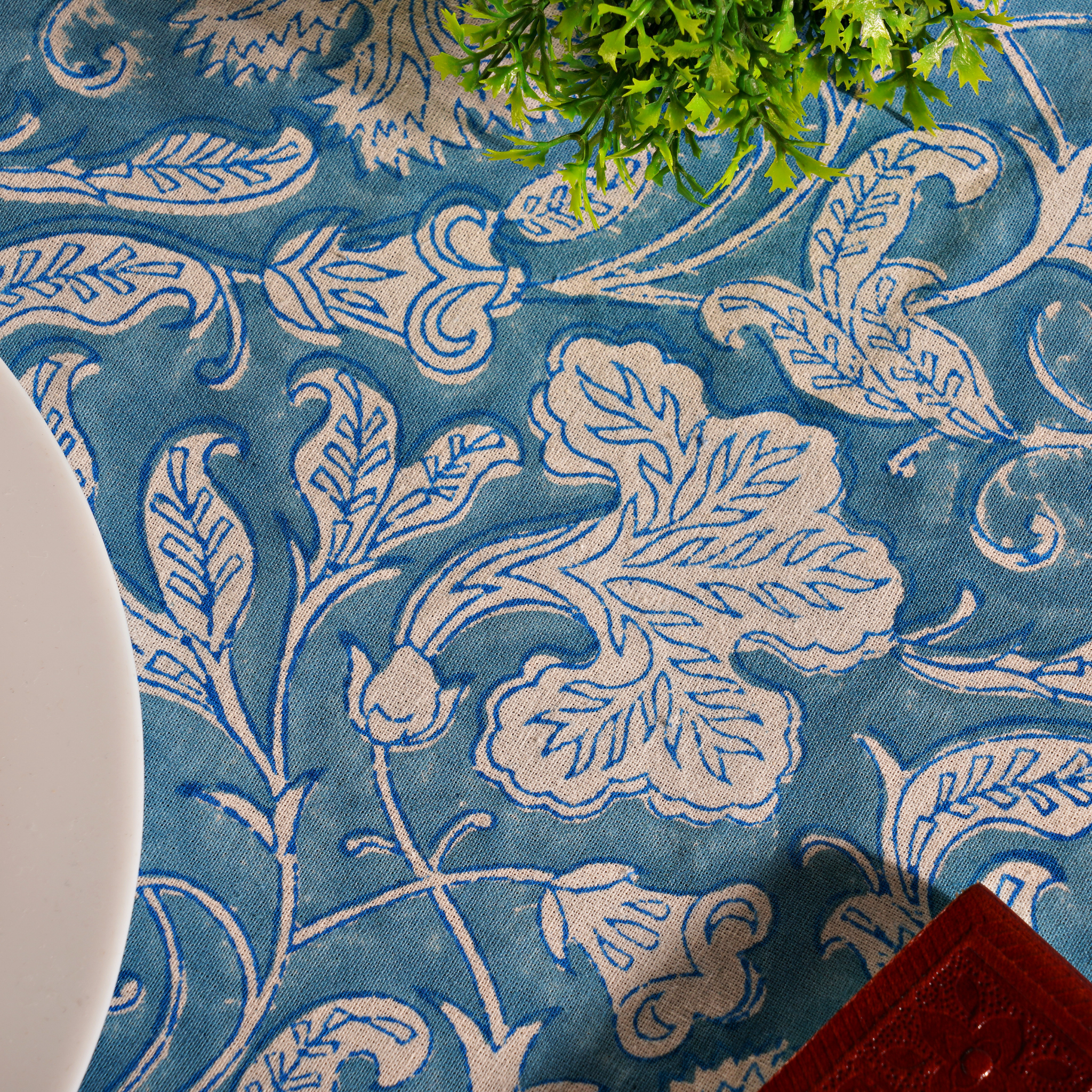 Blue fabric with white floral patterns and a plant on a table.