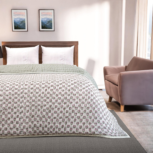 Bedroom with floral-patterned comforter on a bed, armchair, and framed pictures on the wall.