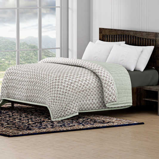 Bed with patterned quilt and white pillows in a room with large windows and a scenic view.