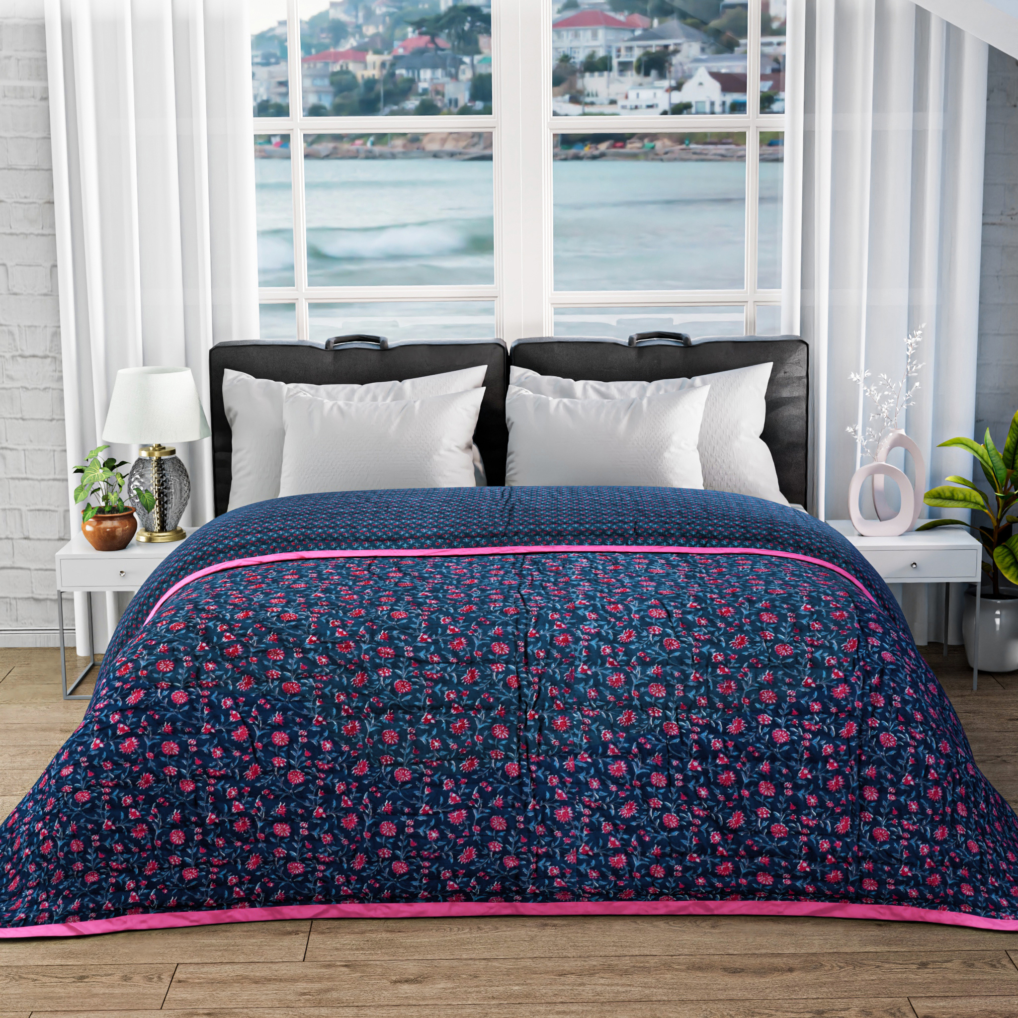 Bed with floral quilt and pillows in a room with large windows showing a view of water and buildings.